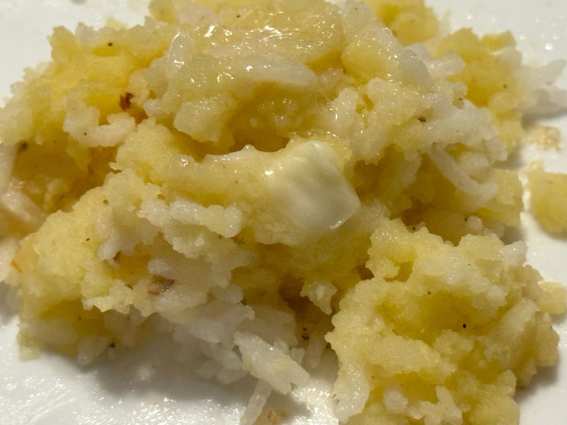 A close up of mashed potatoes and rice on a white plate.