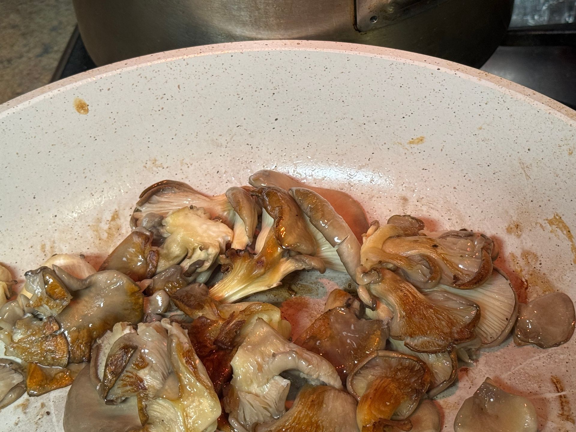 Mushrooms are being cooked in a pan on a stove.