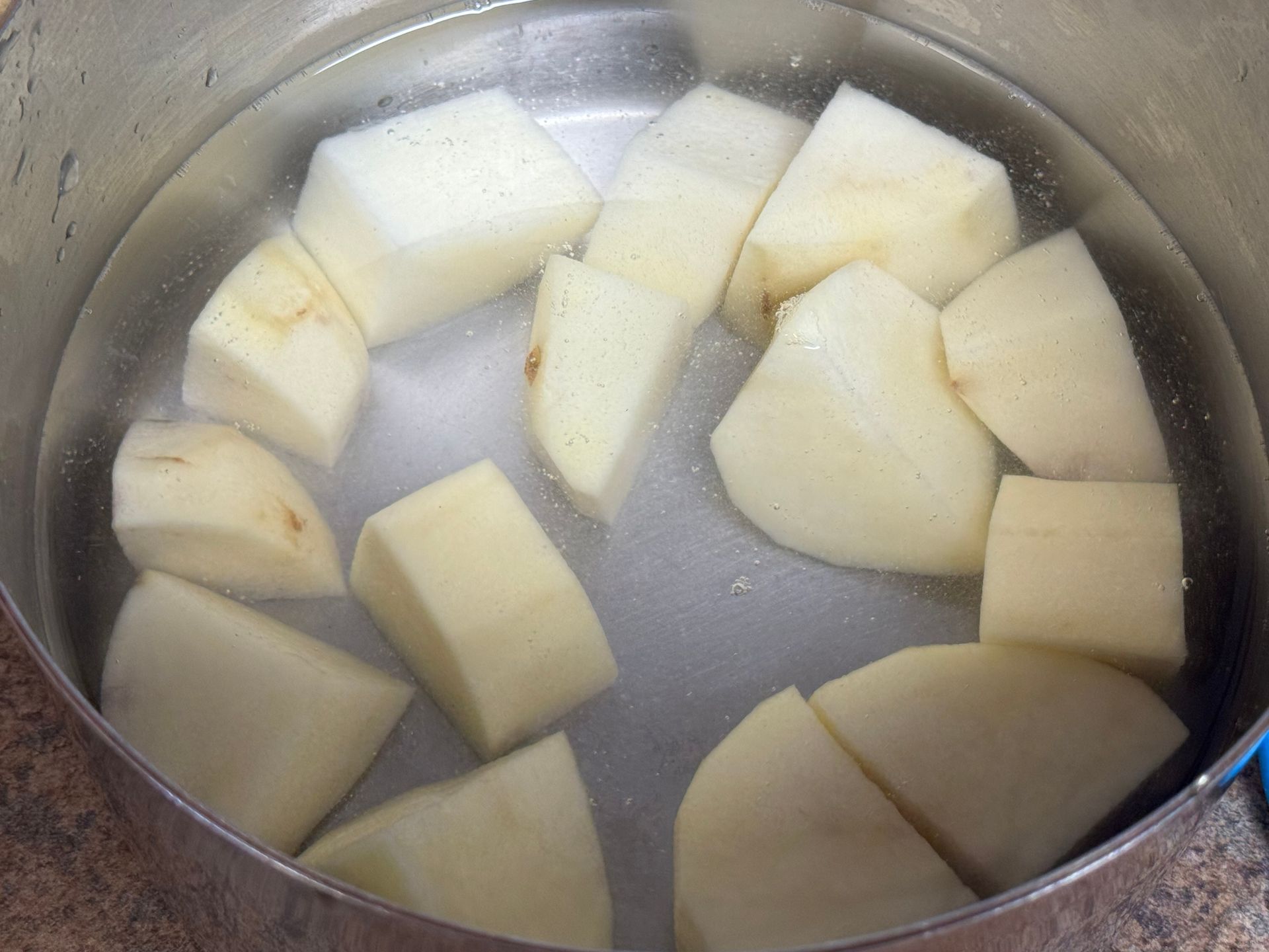 Potatoes are being cooked in a pot of water.