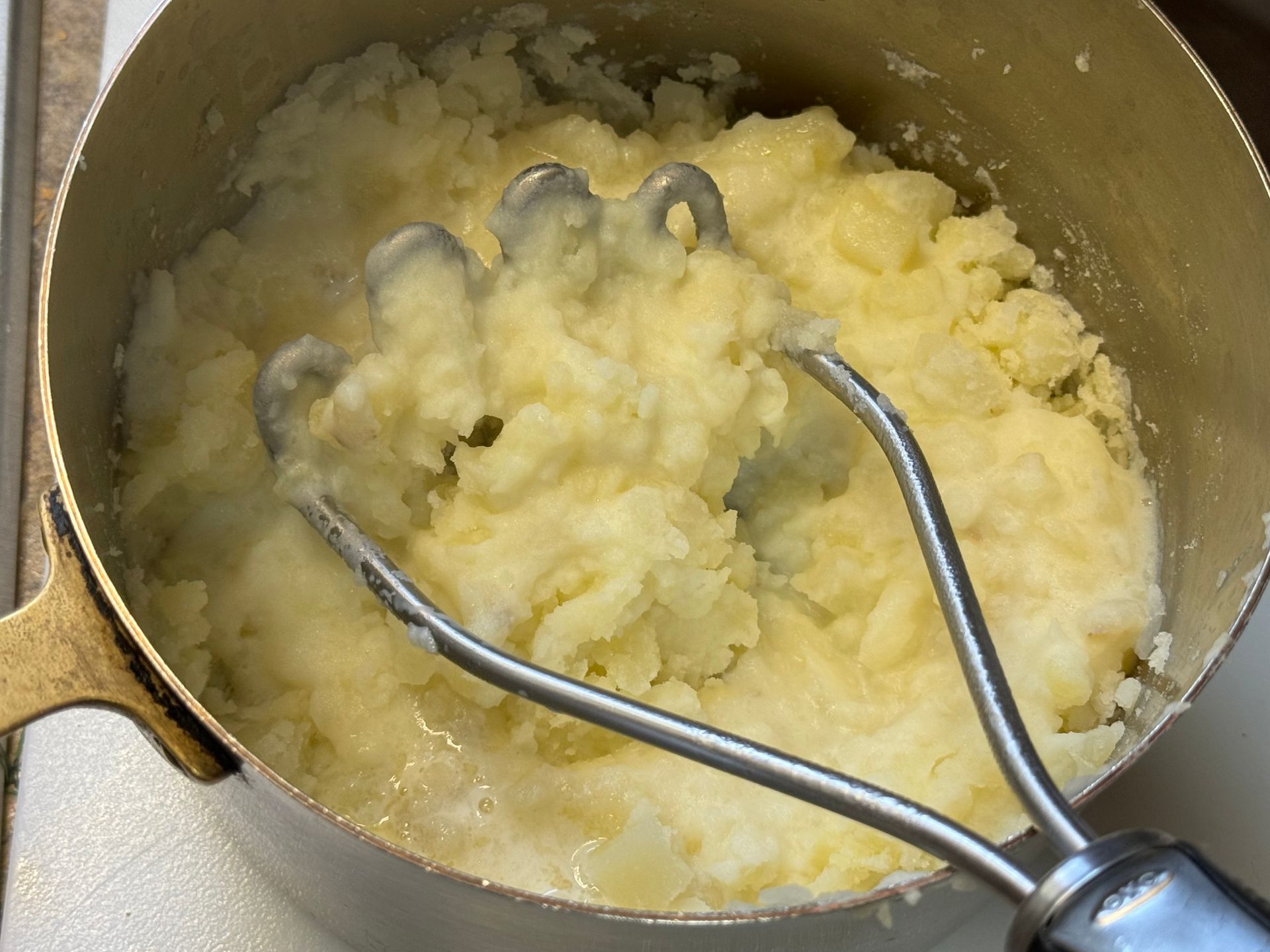 A pot of mashed potatoes with tongs in it