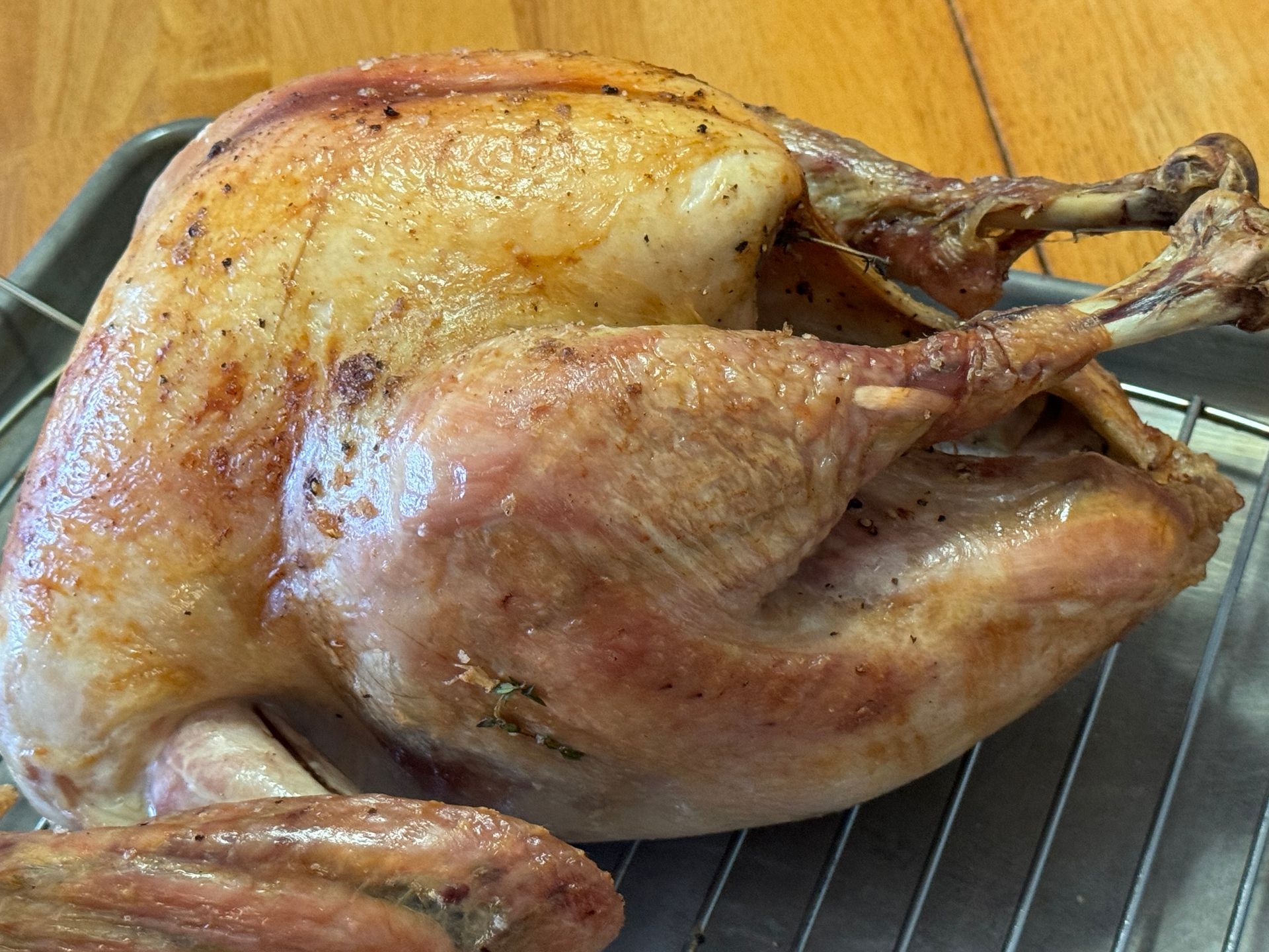 A roasted turkey is sitting on a wire rack on a table.