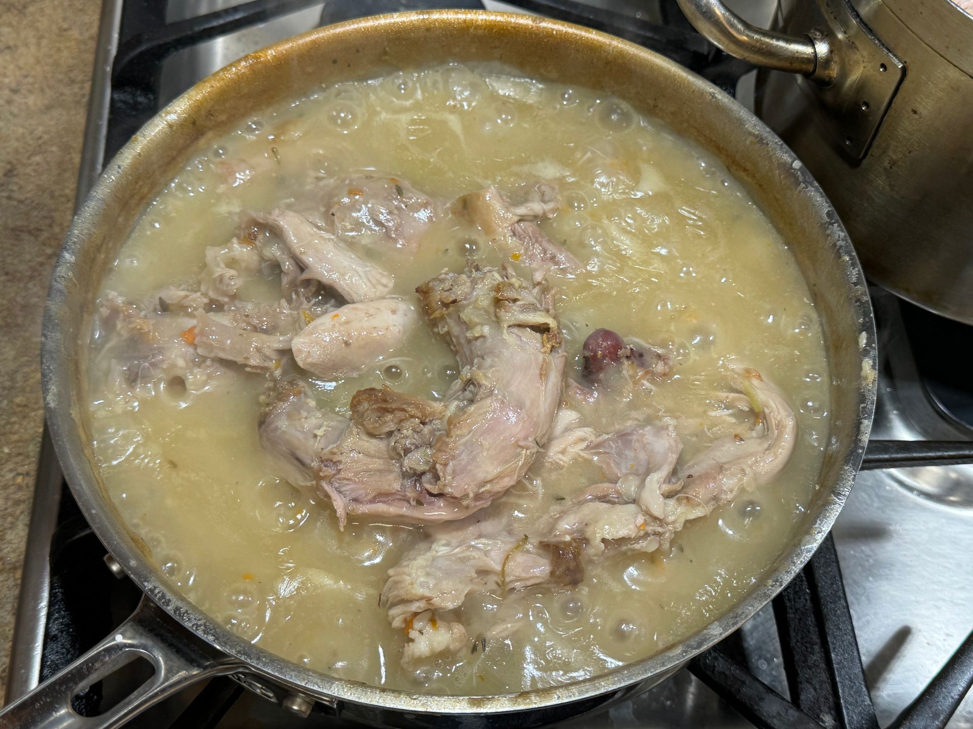A pan of chicken soup is cooking on a stove.