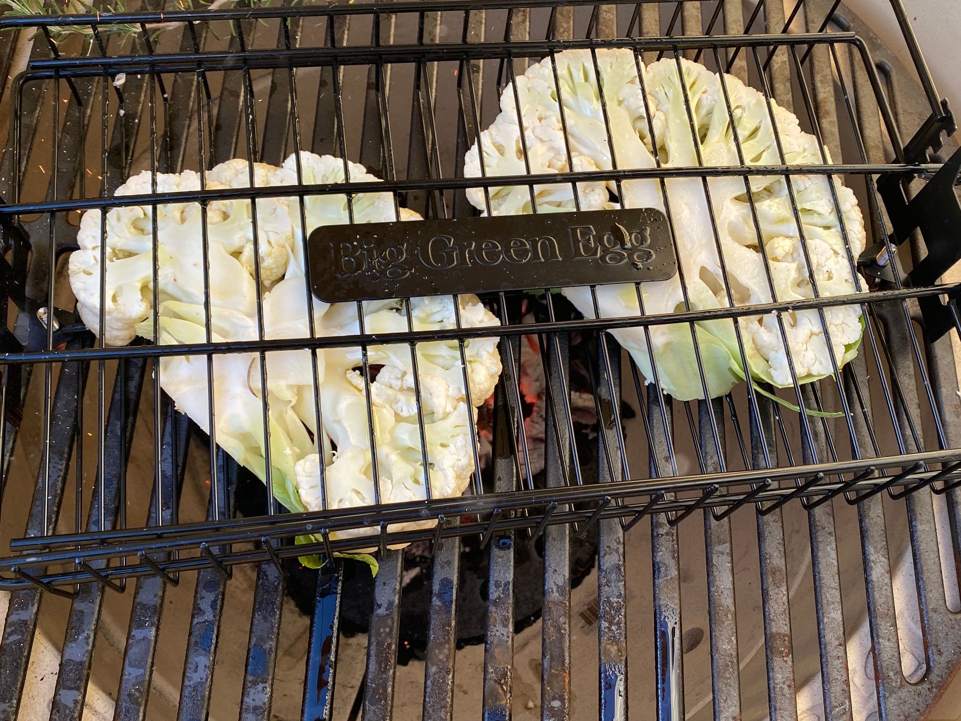 Two pieces of cauliflower are cooking on a grill.