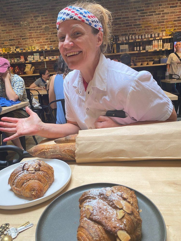 A woman is sitting at a table with two plates of food.