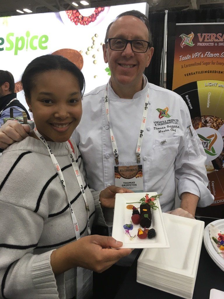 A man and a woman are posing for a picture while holding a plate of food.