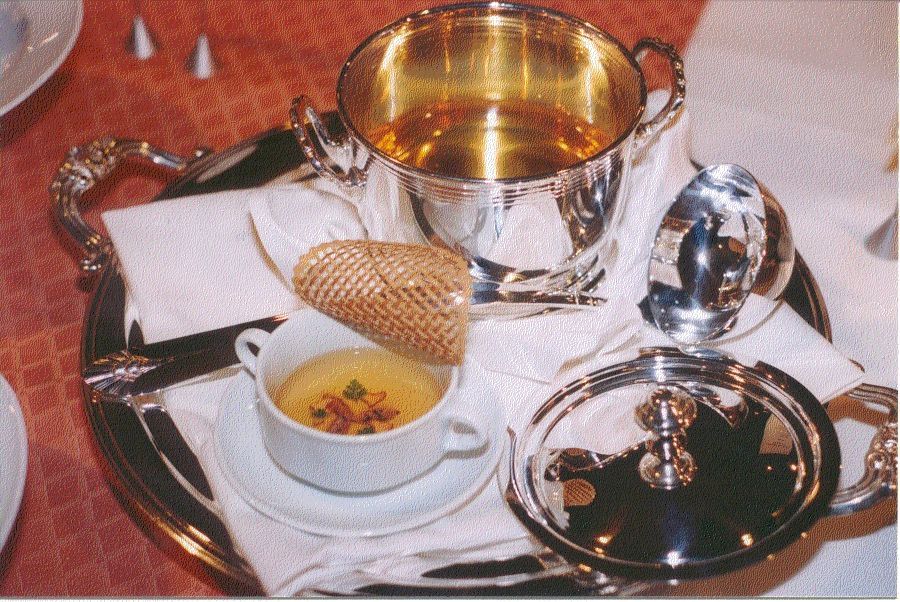 A silver tray with a cup of soup on it