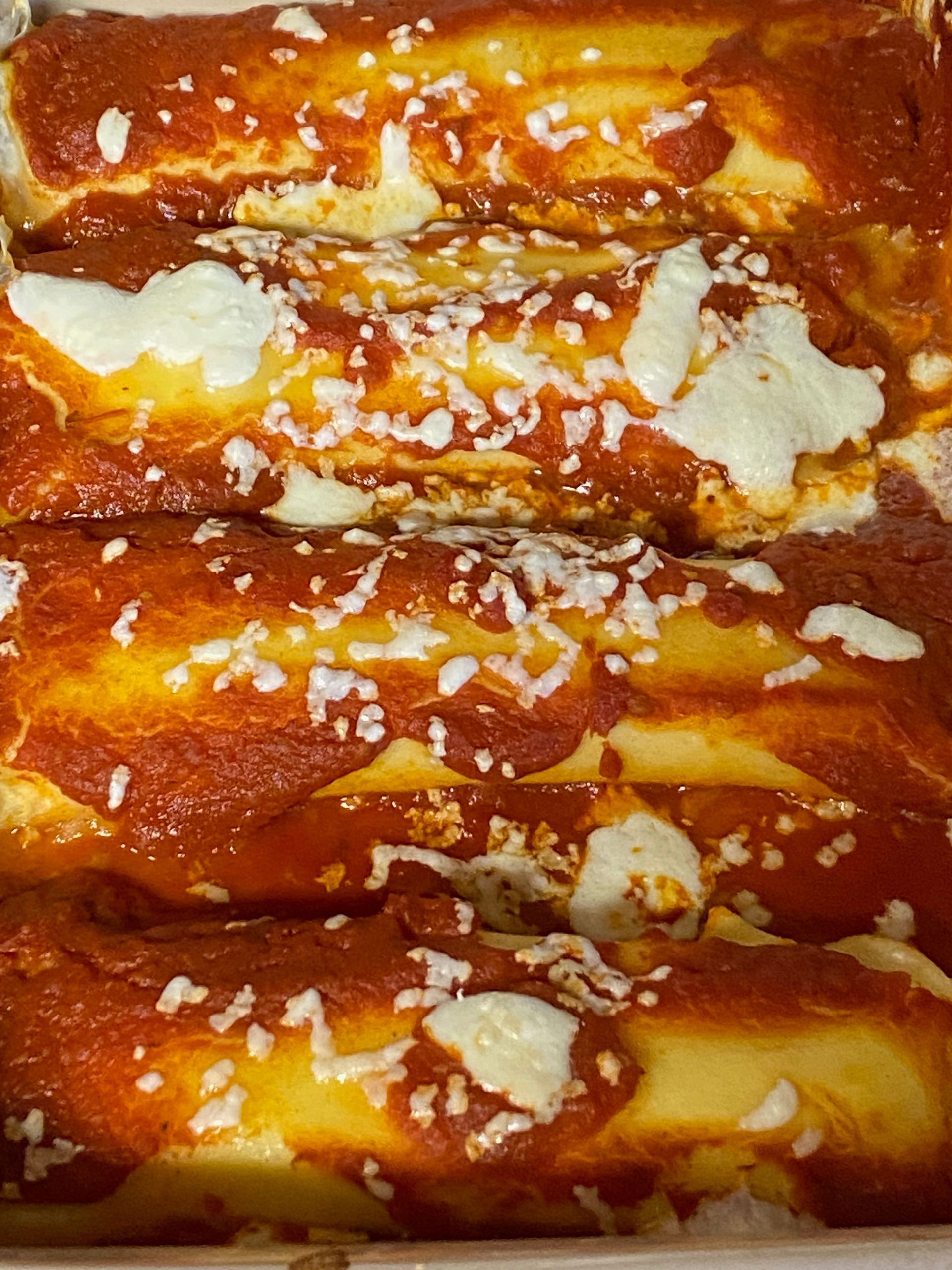 A casserole dish filled with enchiladas covered in sauce and cheese.