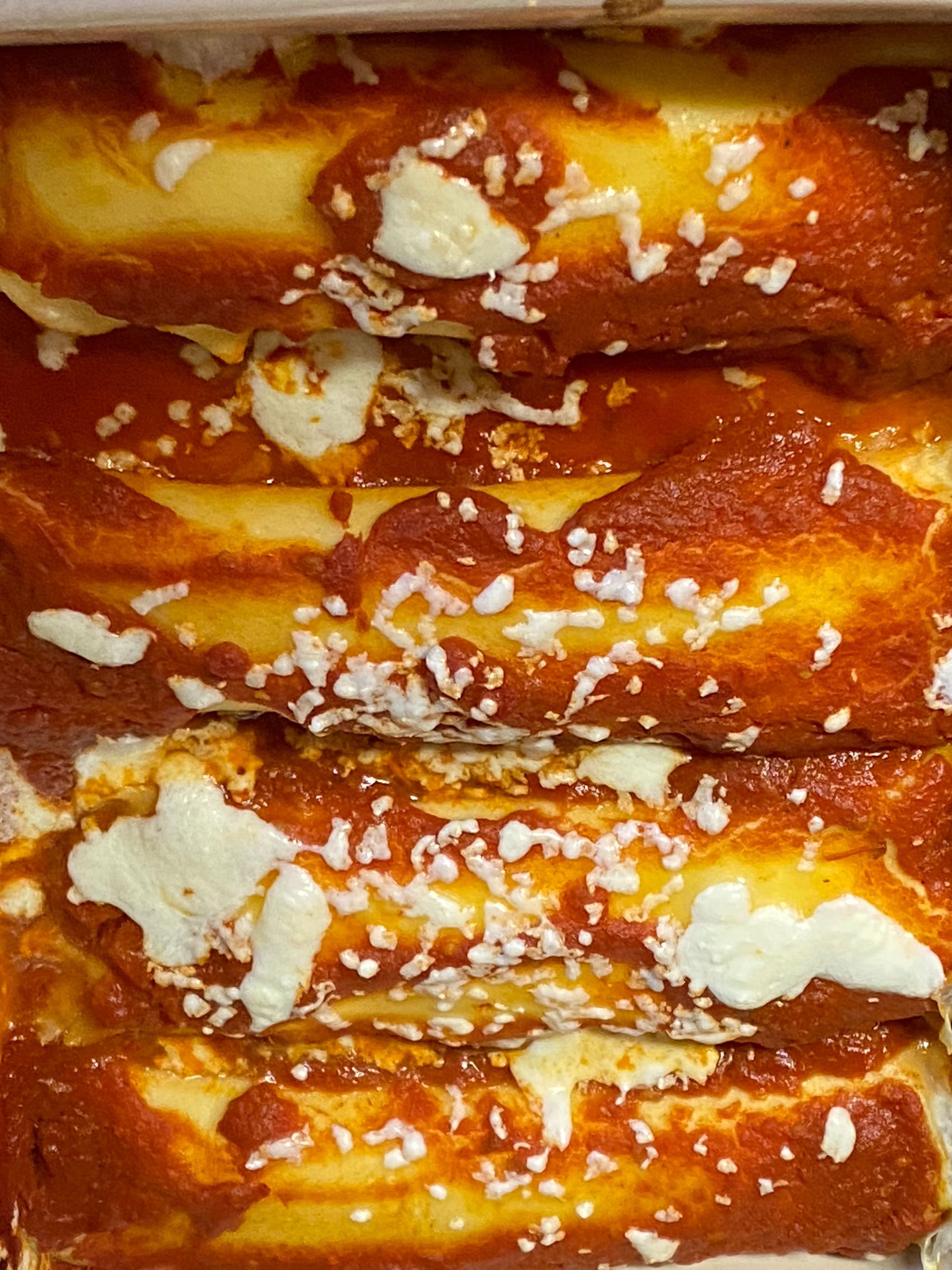 A close up of a stack of pretzels covered in sauce and cheese.