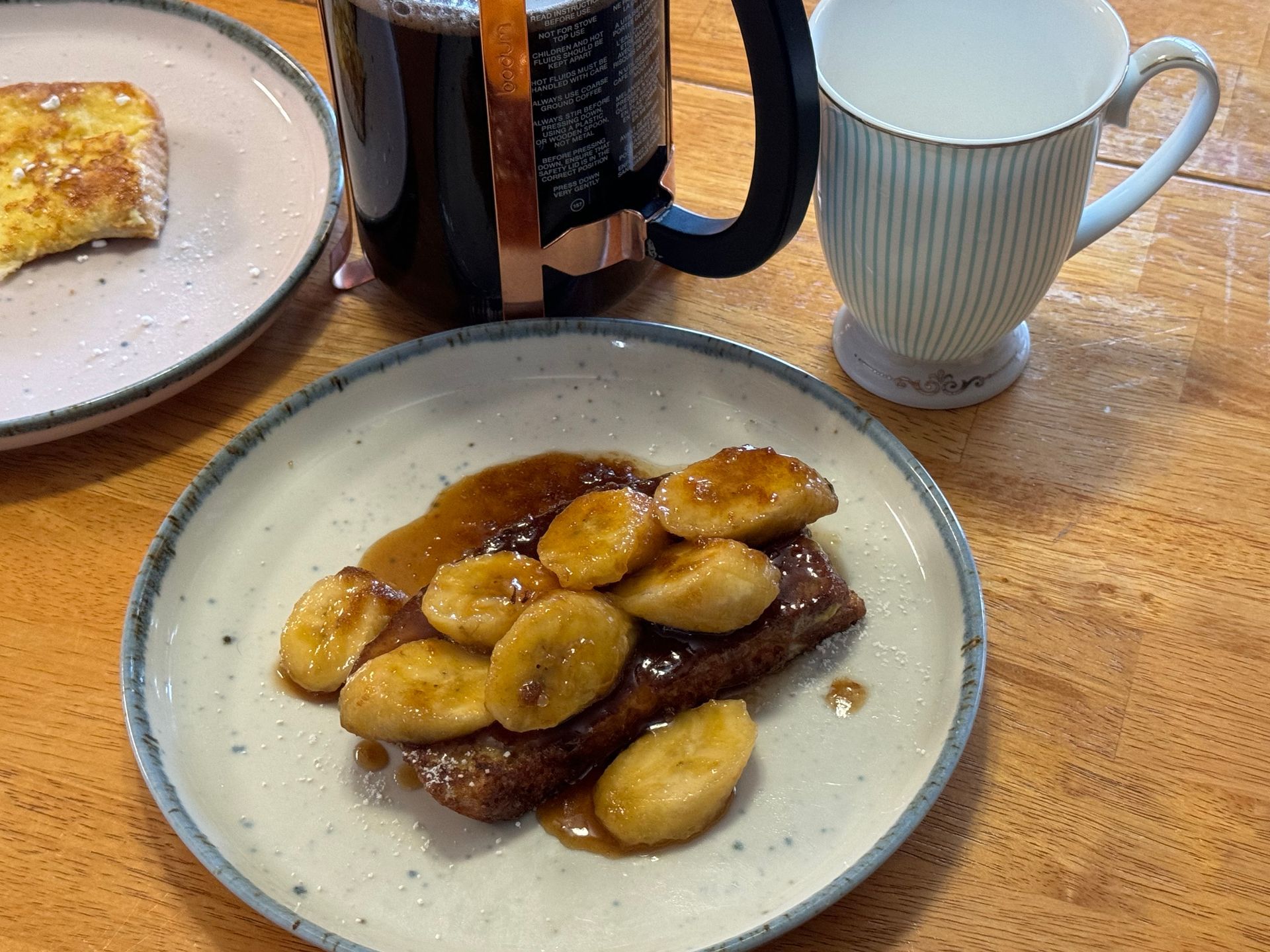 A plate of food with bananas and a cup of coffee on a table.