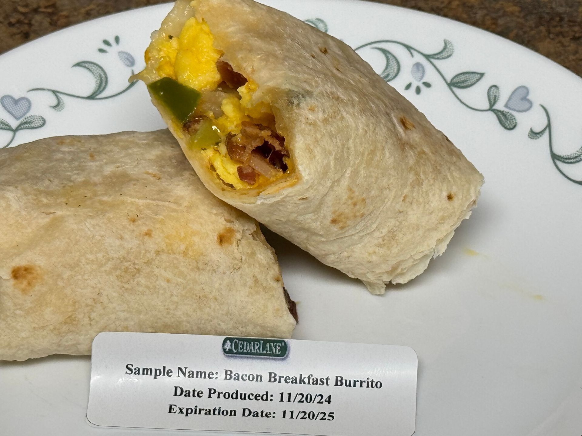 A burrito on a plate with guacamole and sour cream