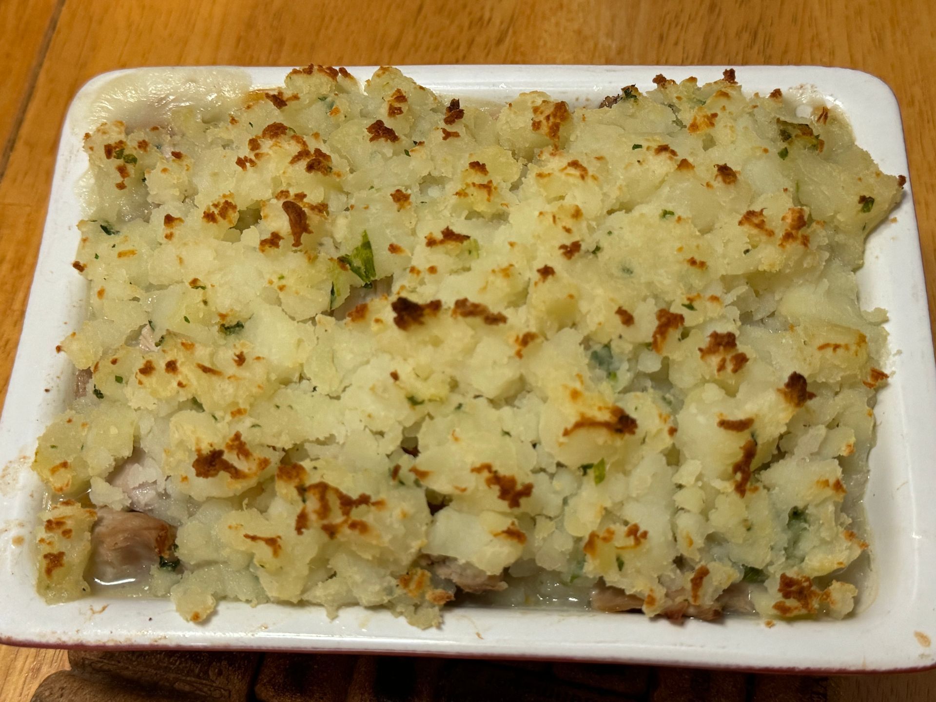 A white casserole dish filled with mashed potatoes and meat