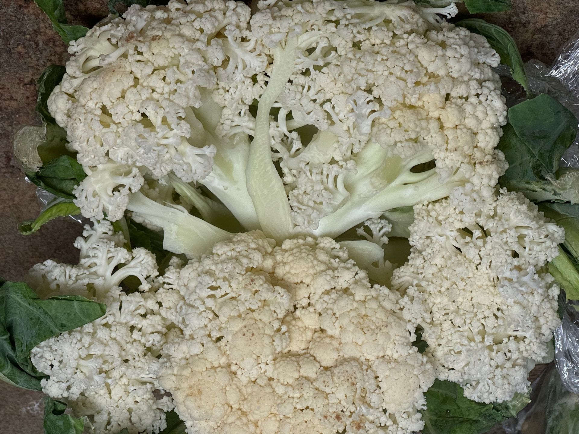 A close up of a white cauliflower with green leaves