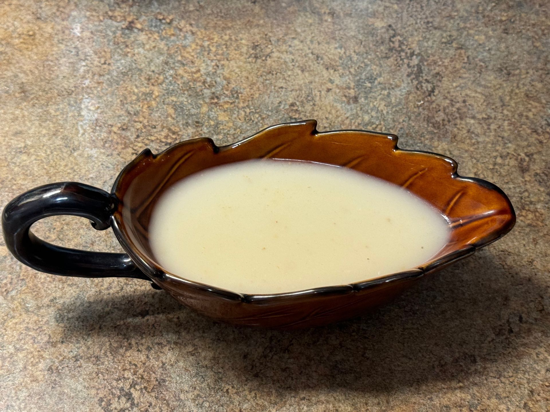 A brown leaf shaped bowl filled with white liquid