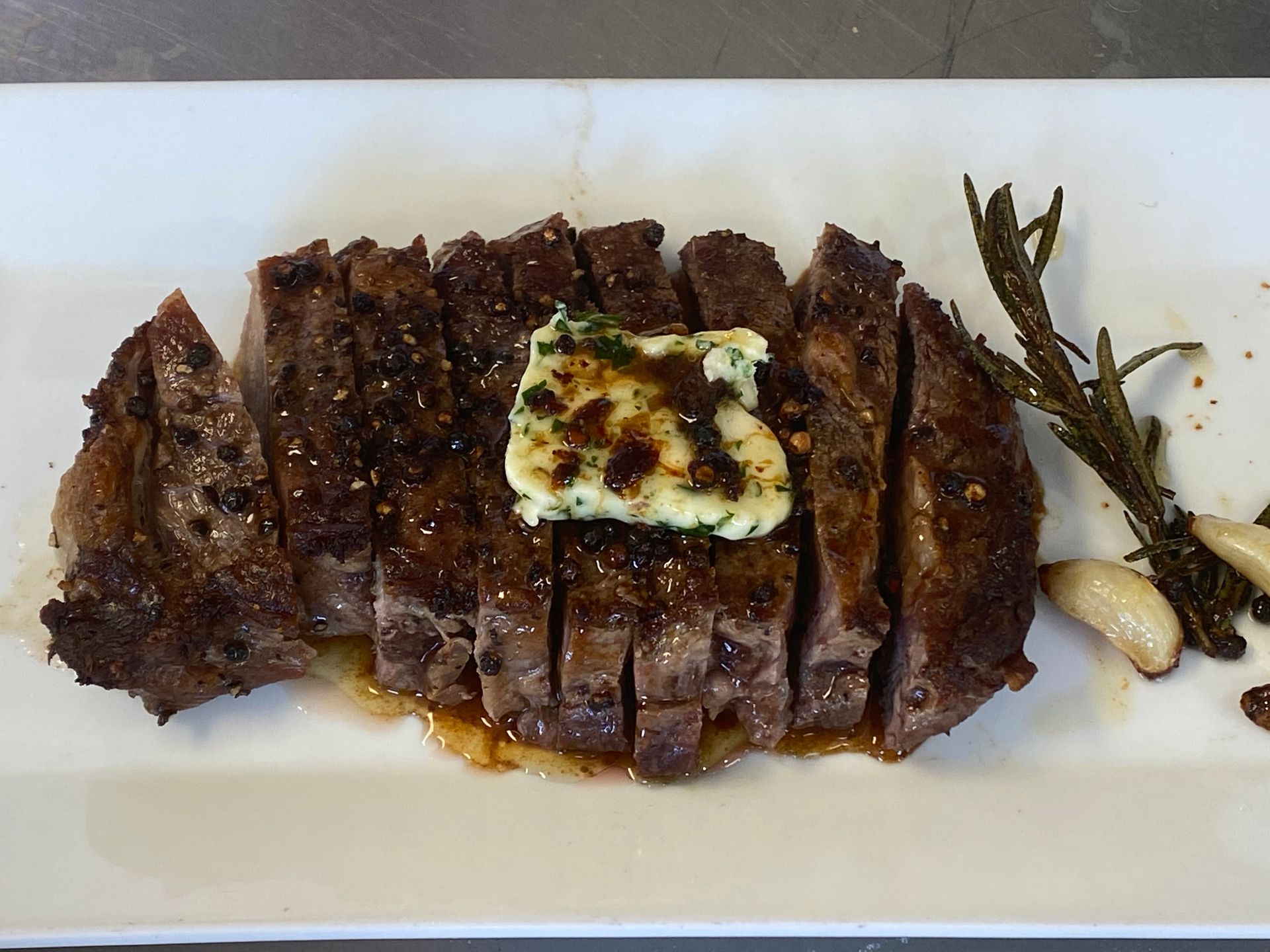 A steak with butter on top of it on a white plate