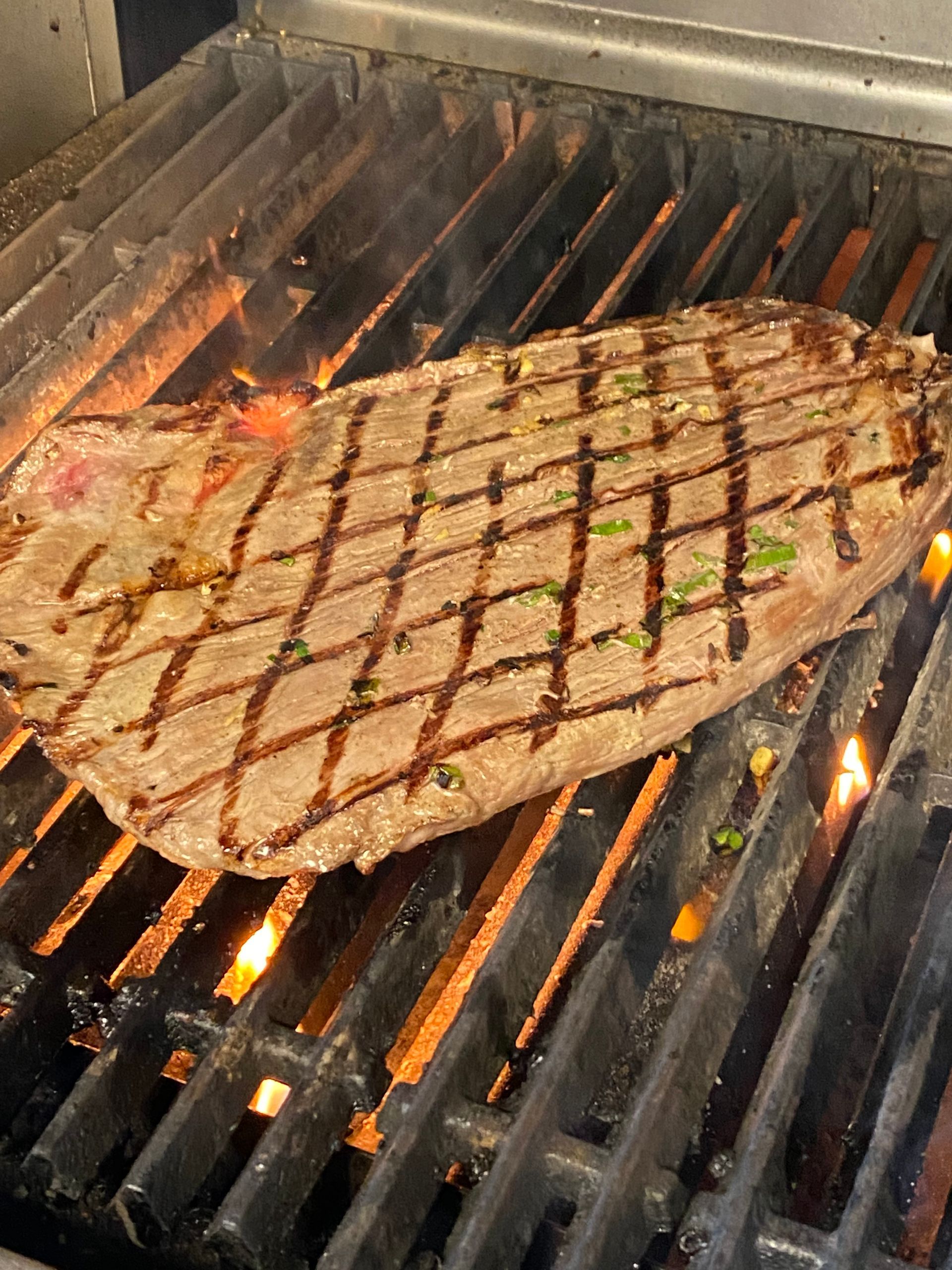 A large piece of meat is cooking on a grill.
