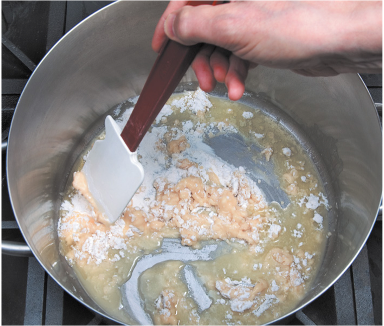 A person is stirring something in a pot with a spatula