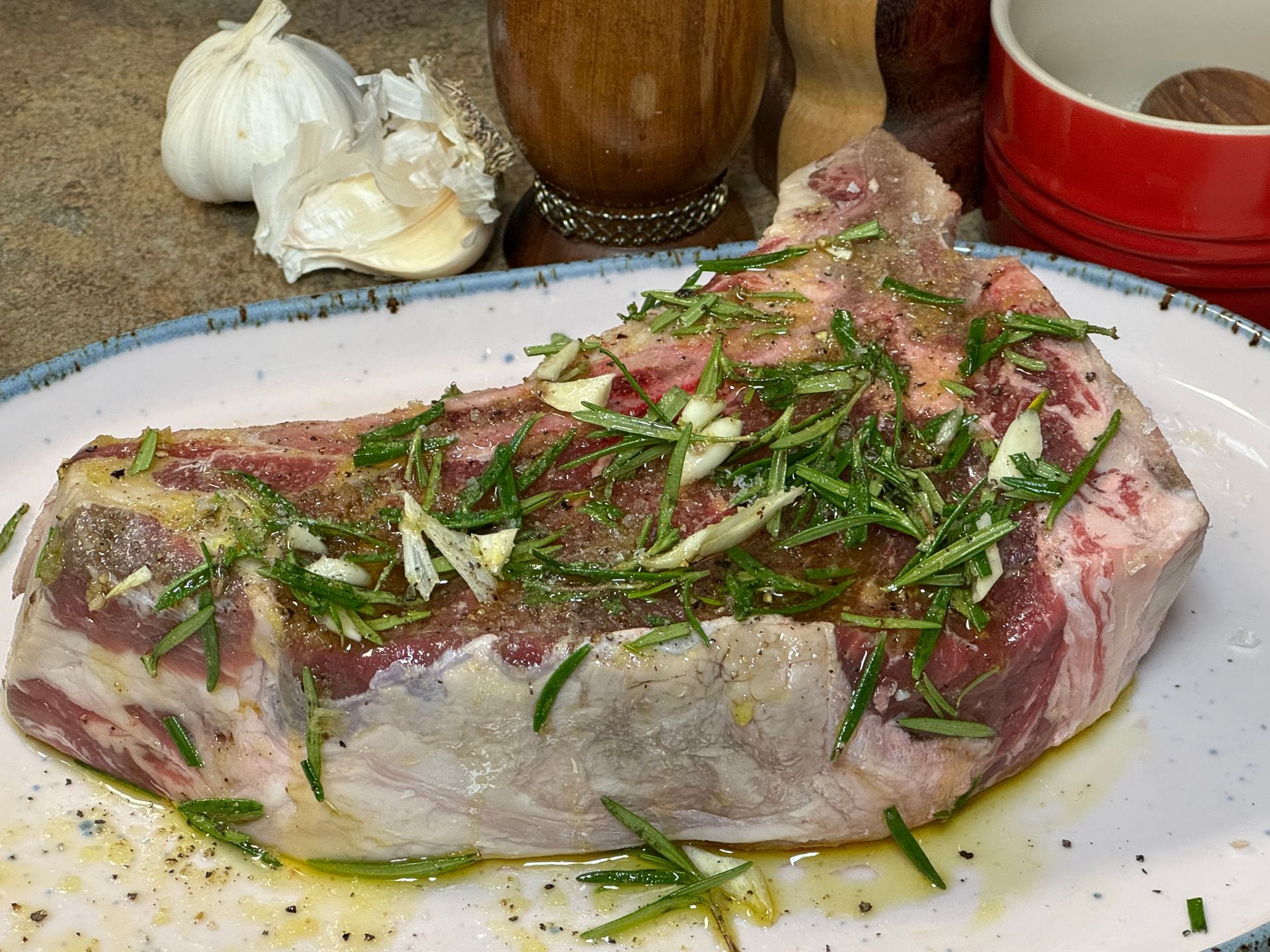 A large piece of meat on a plate with herbs and garlic