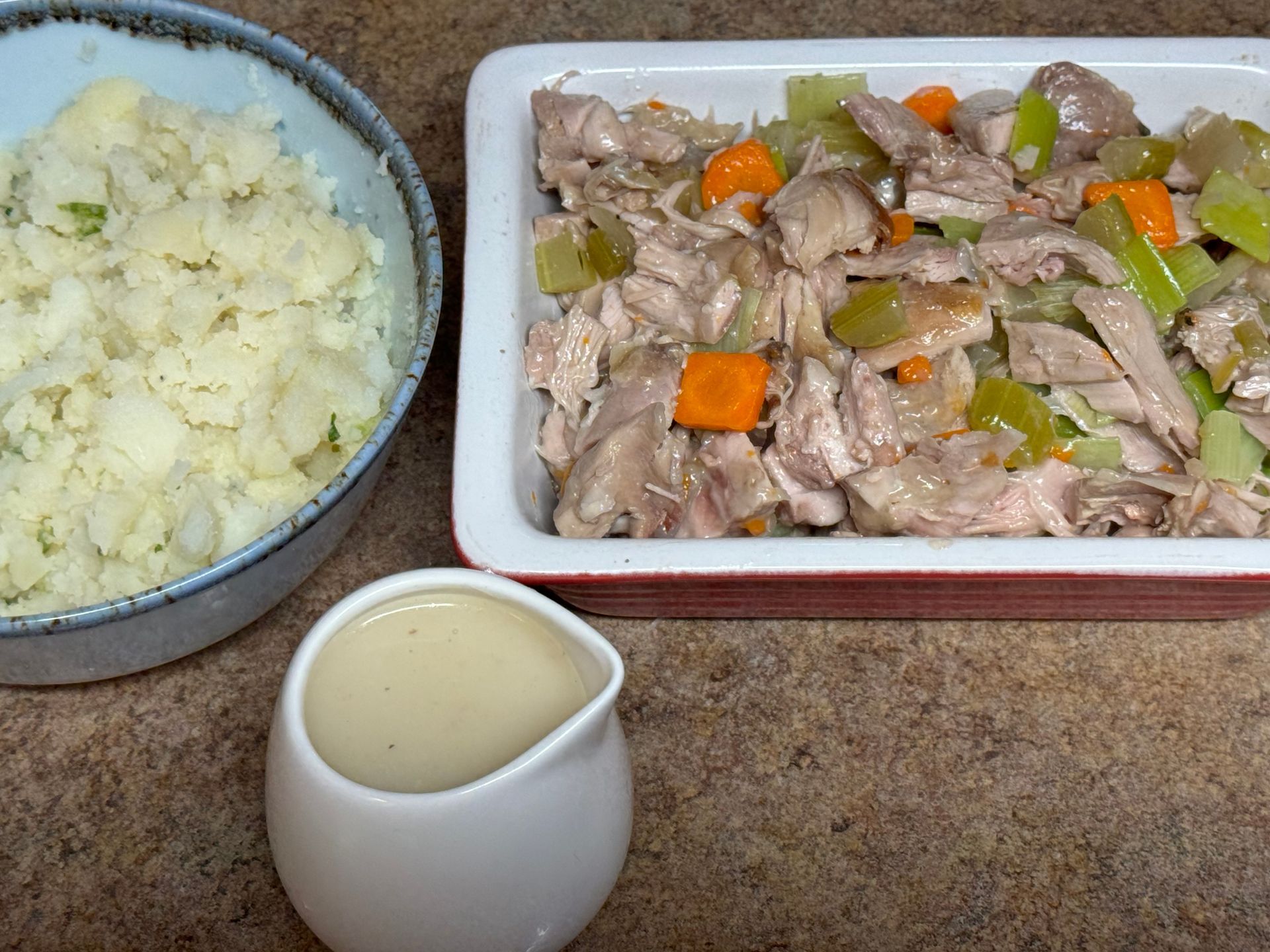 A bowl of mashed potatoes next to a bowl of chicken and vegetables.