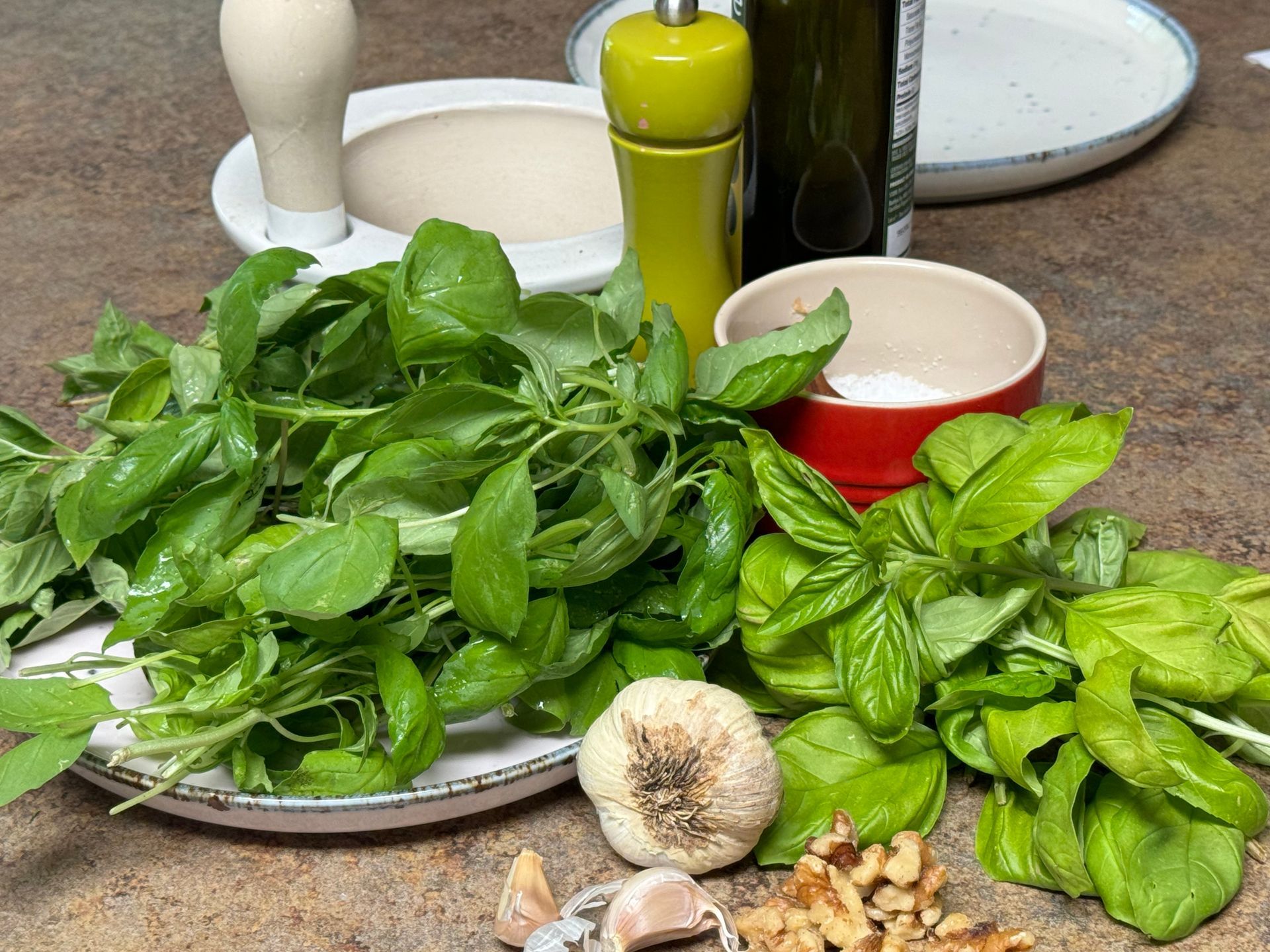 A table topped with a variety of vegetables including basil garlic and walnuts