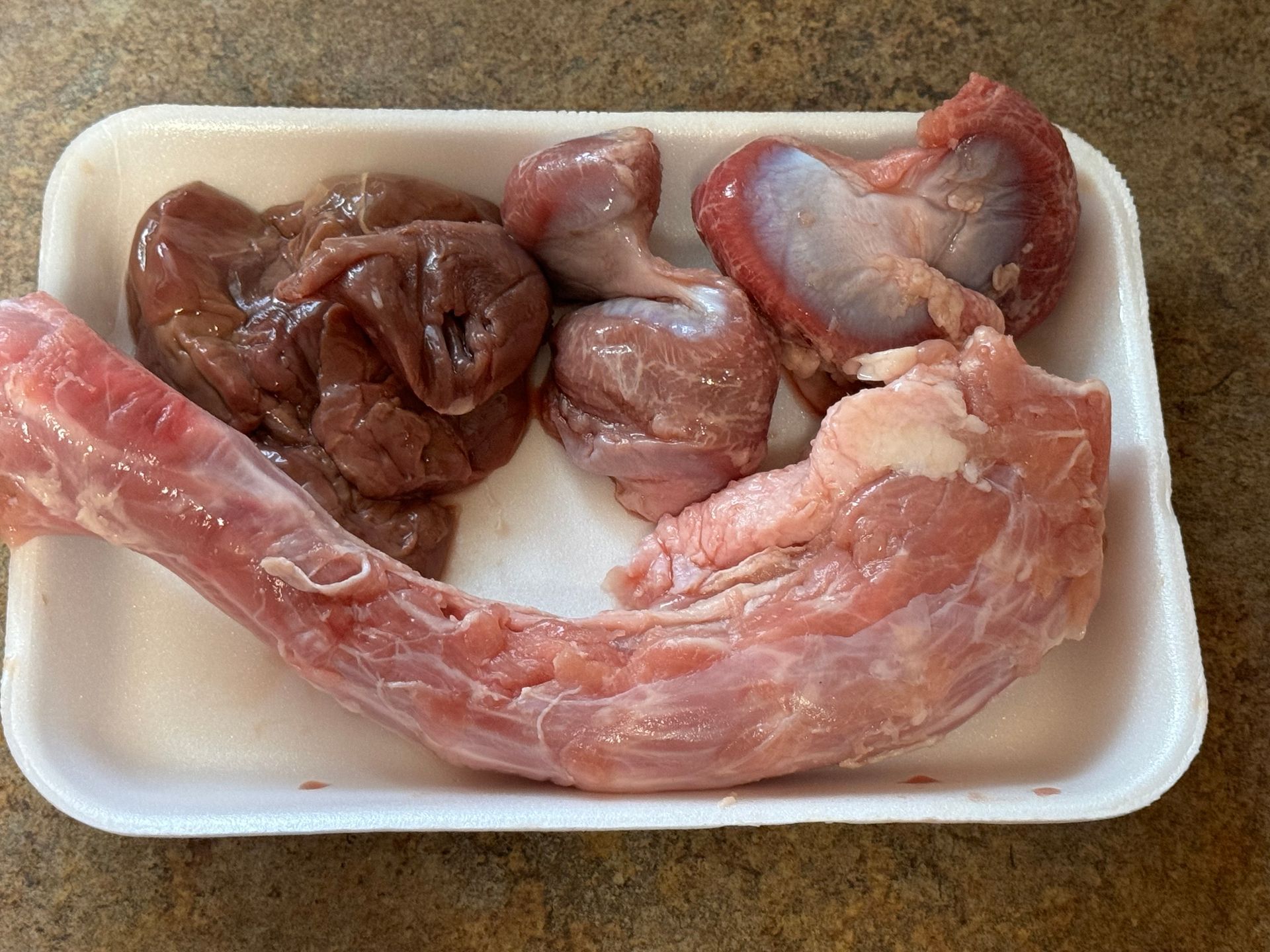 A white styrofoam tray filled with meat and livers
