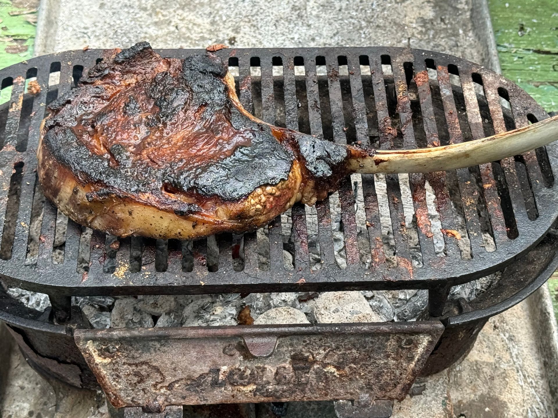 A large steak is being cooked on a grill.