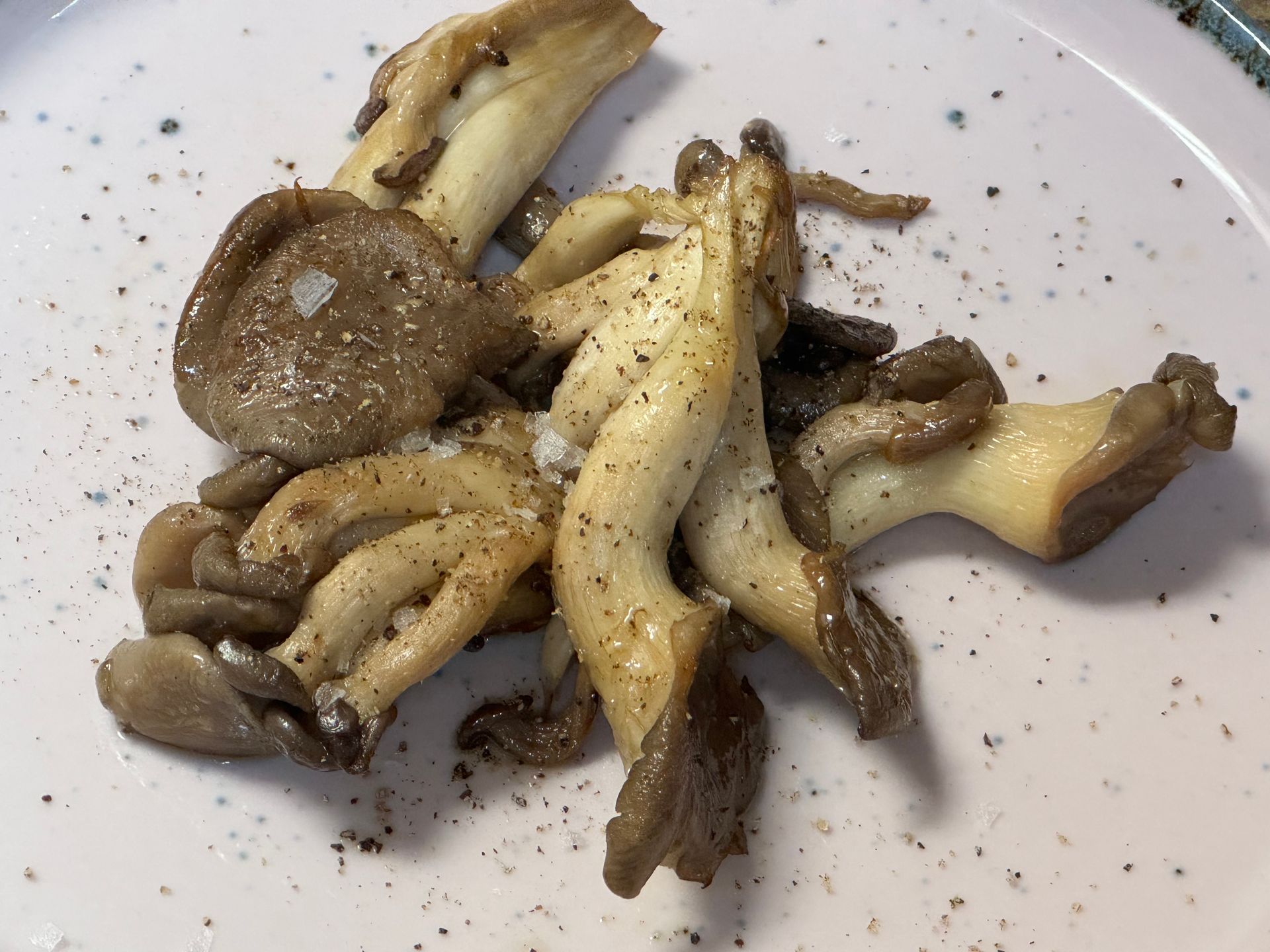 A white plate topped with mushrooms and salt and pepper