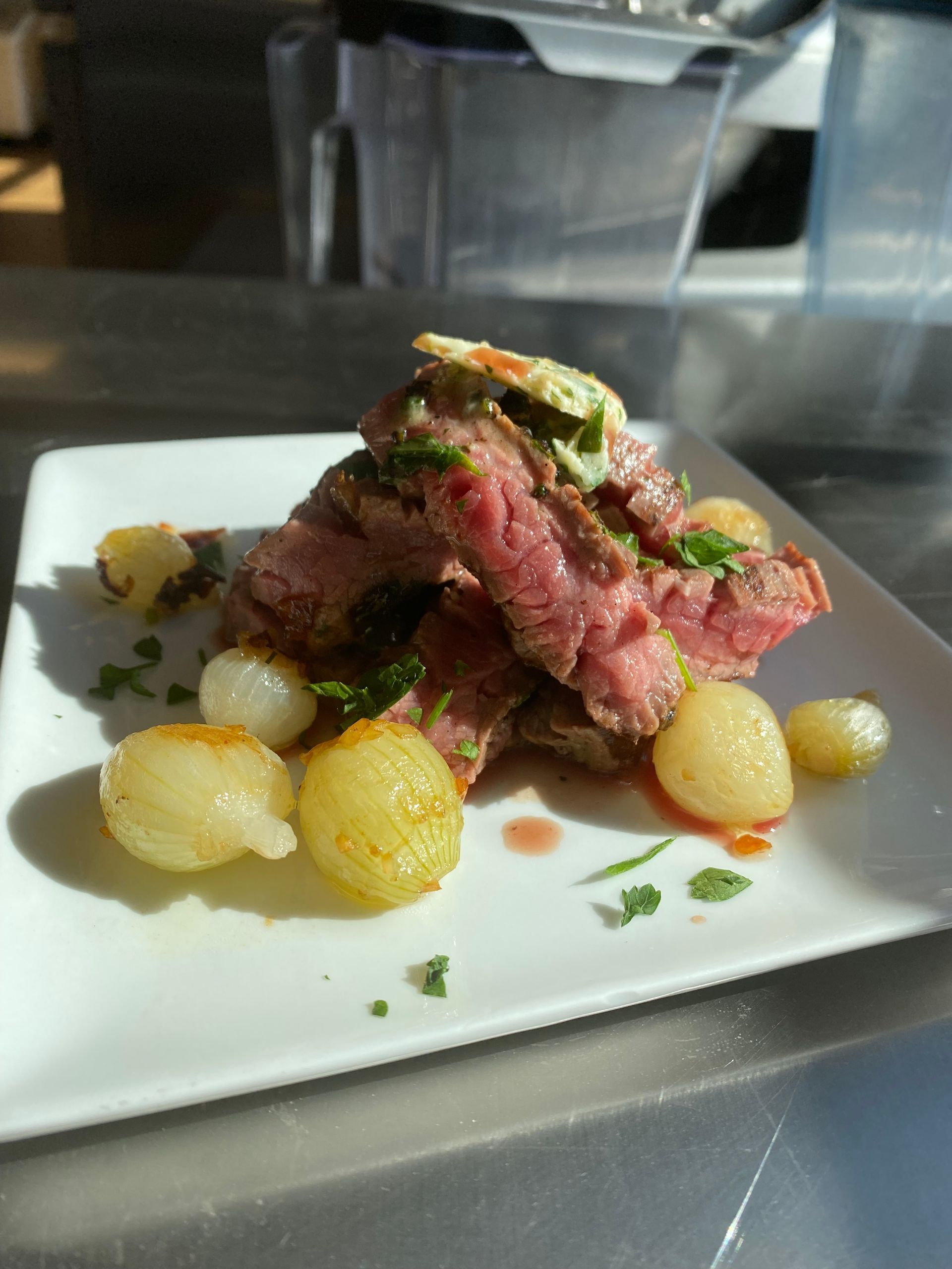 A white plate topped with meat and potatoes on a table