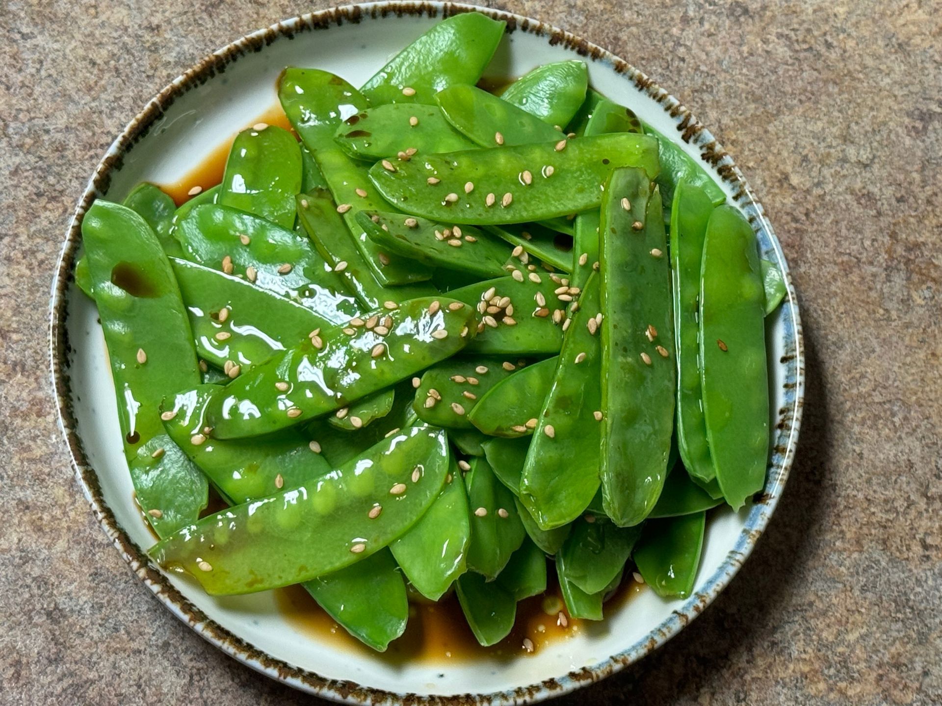 A plate of green beans with sesame seeds on top
