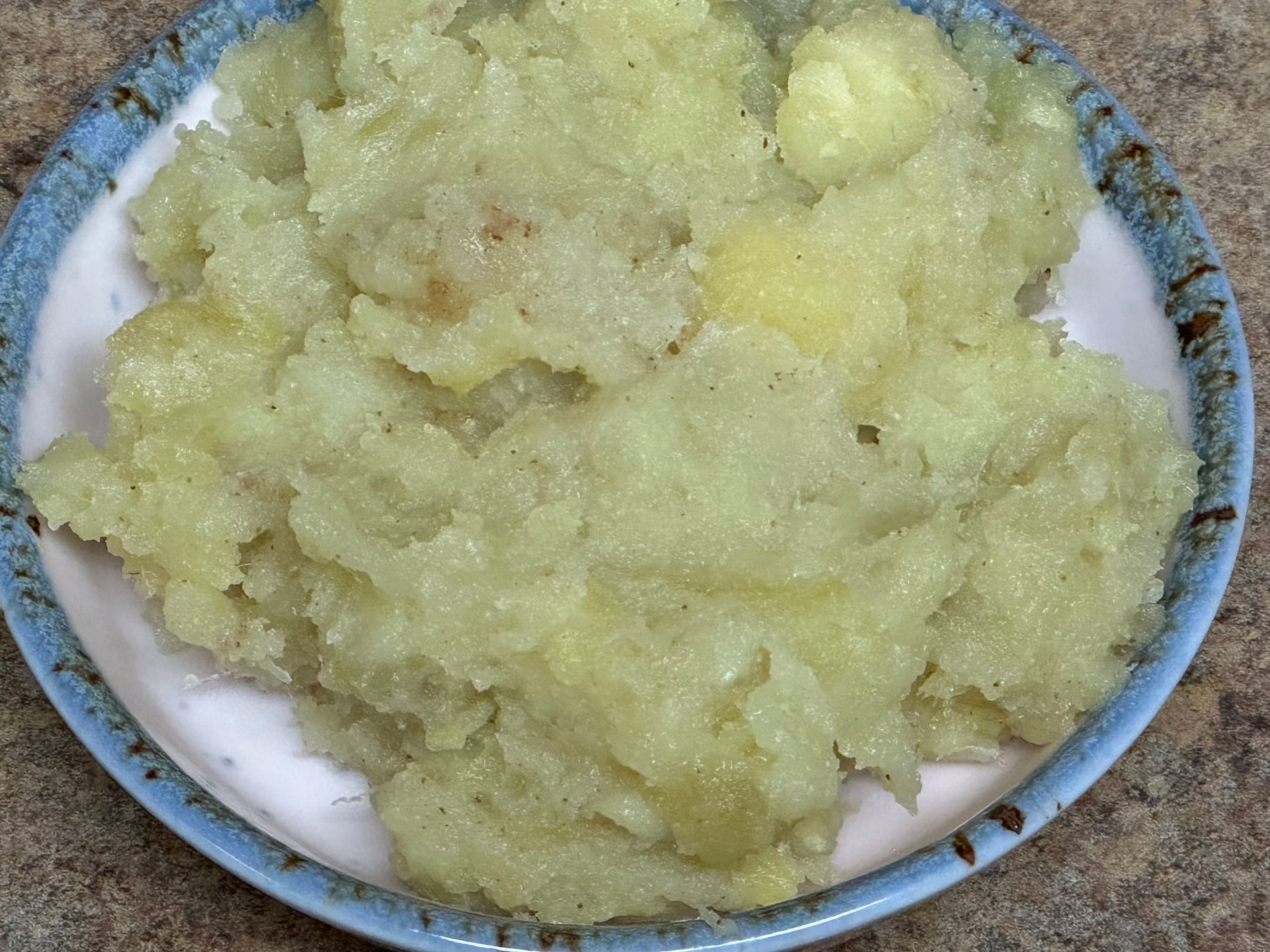 A blue and white plate topped with mashed potatoes