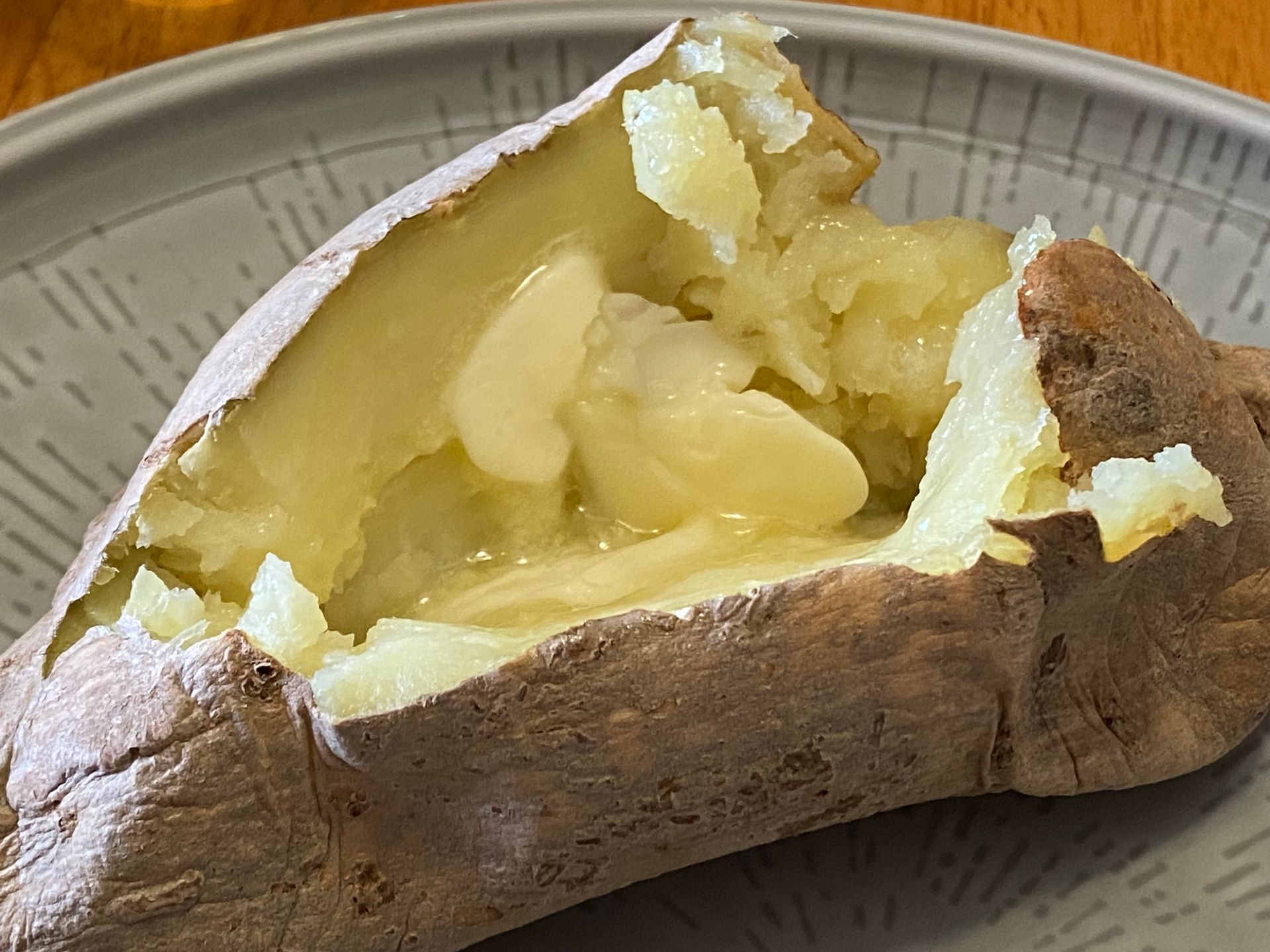 A baked potato is cut in half on a plate