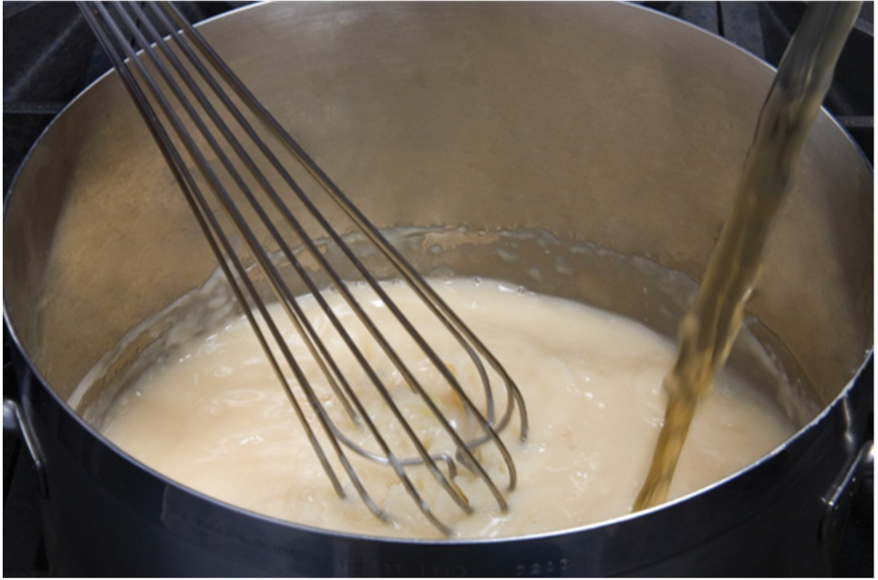 A whisk is being used in a pot of liquid