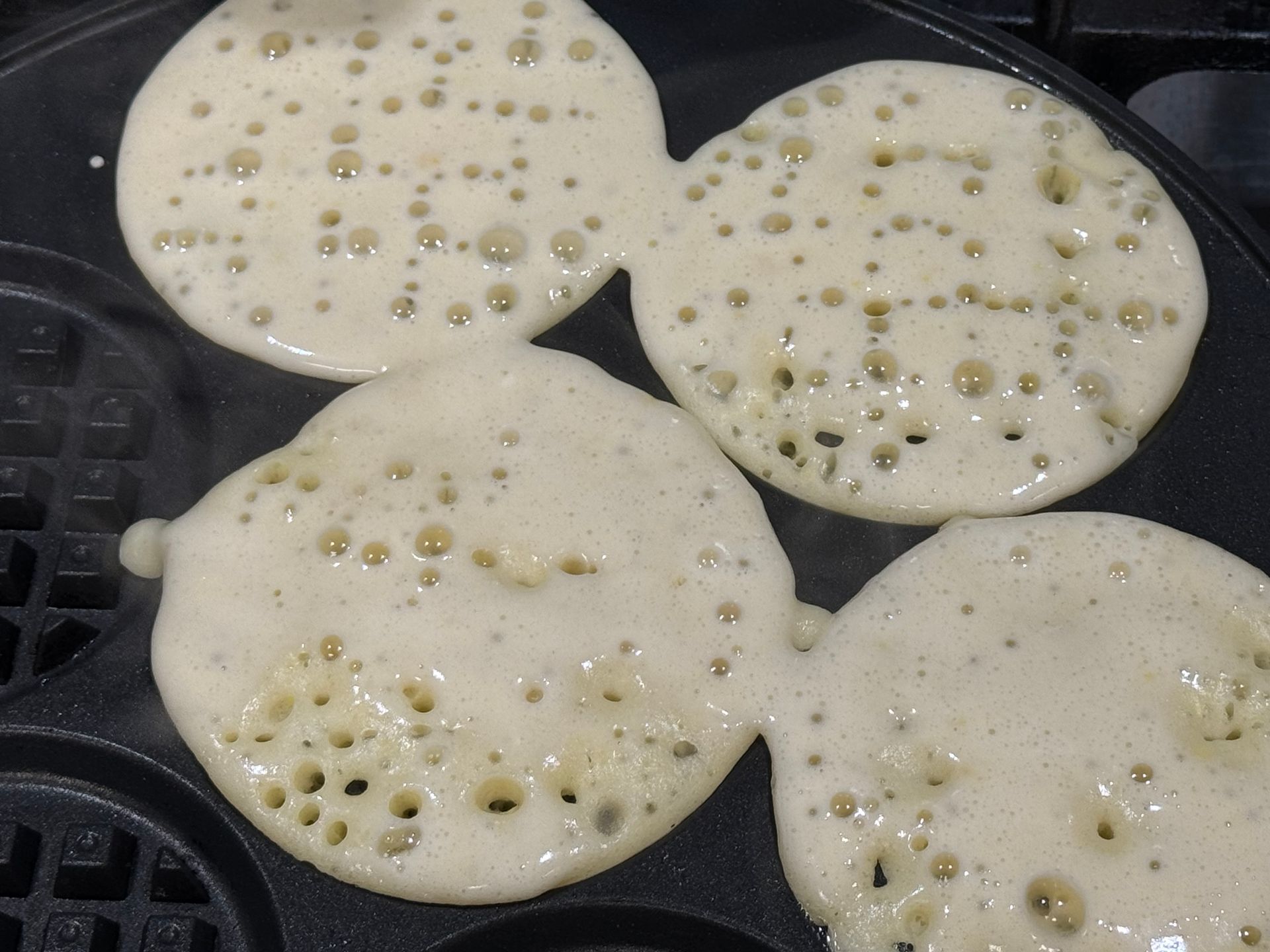 Pancakes are being cooked in a pan with holes in them