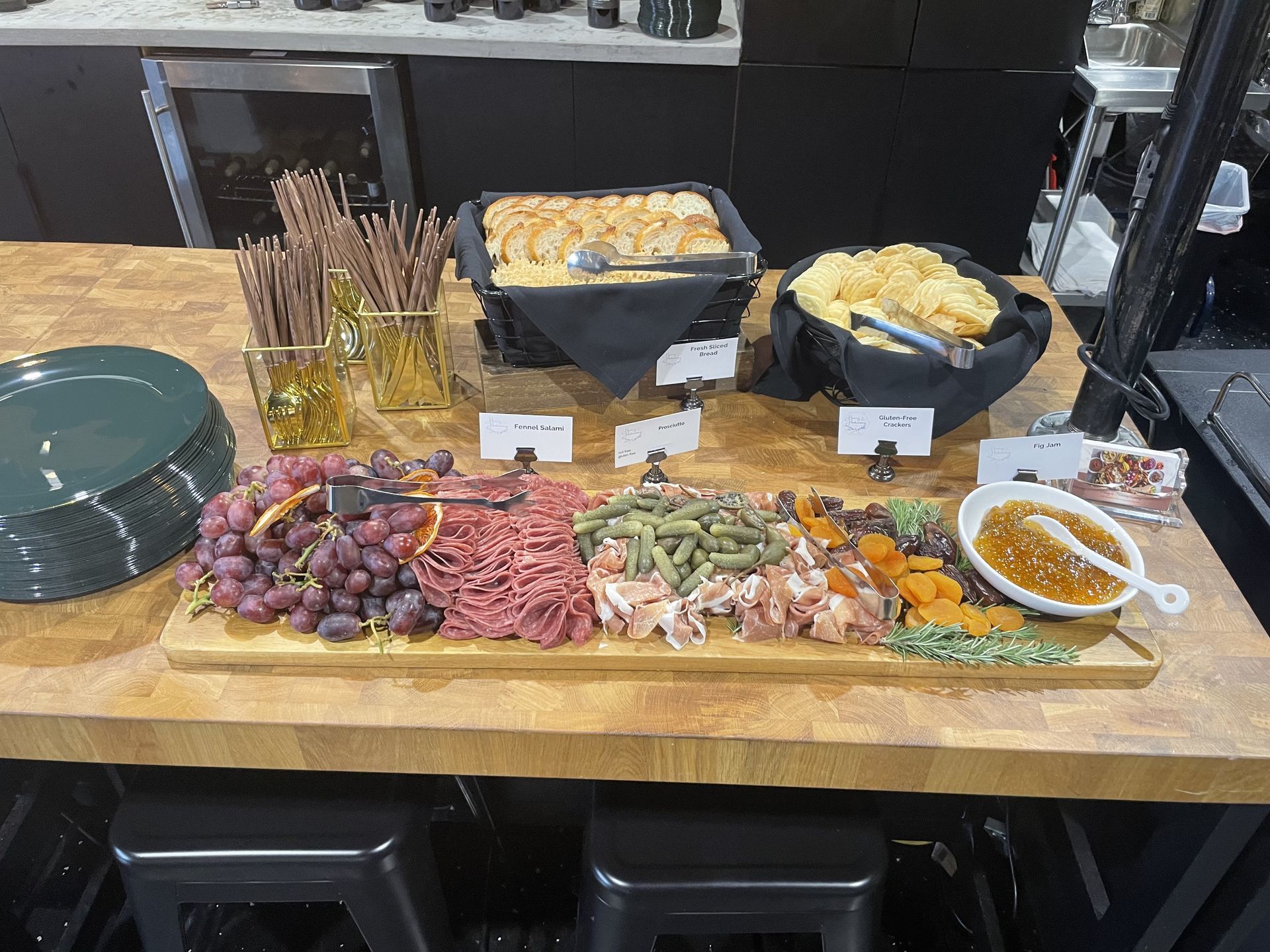 Buffet table with assorted appetizers, cheese, crackers, grapes, cured meats, and dipping sauces