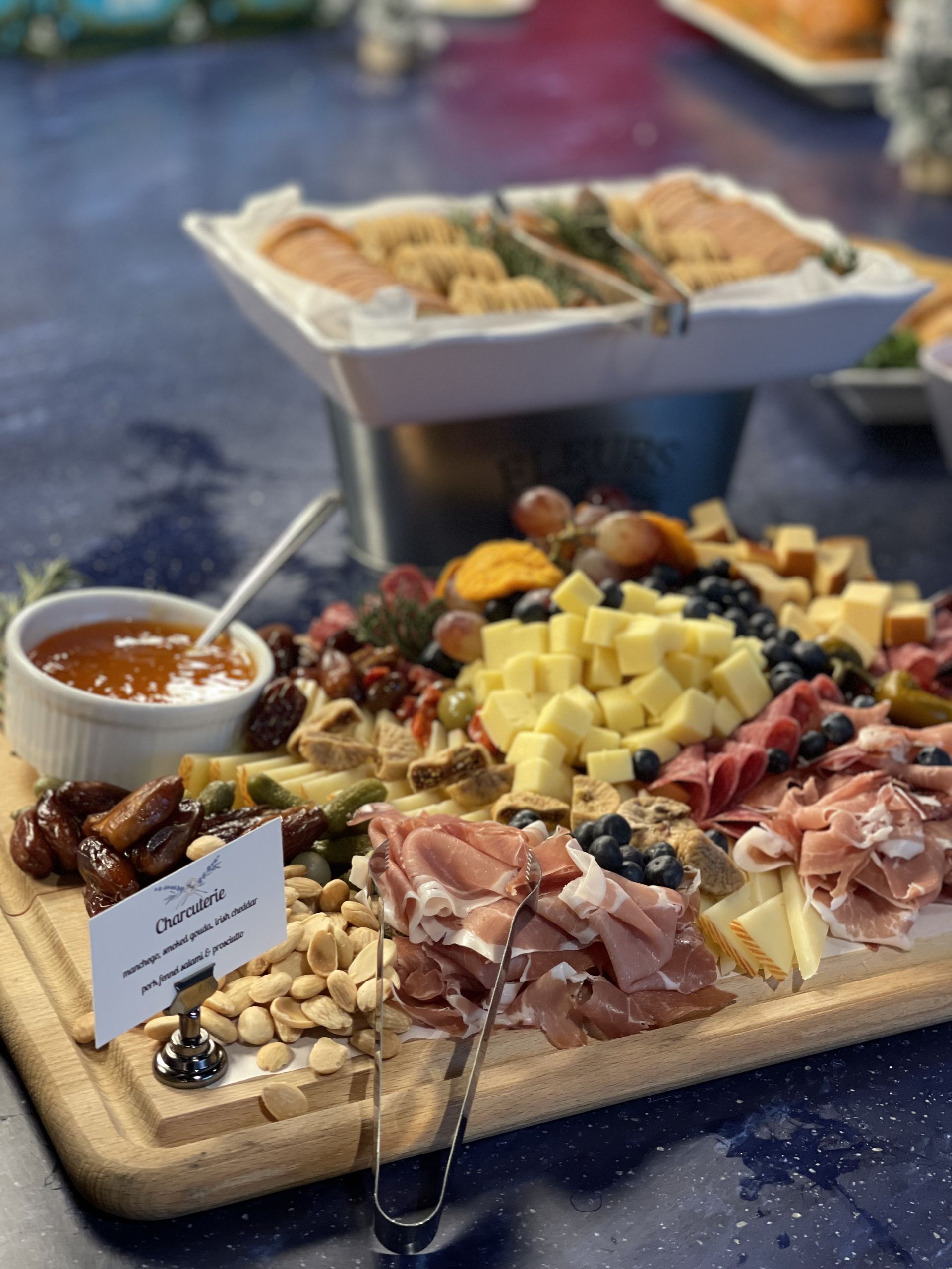 Charcuterie board with cheese, meats, nuts, and dipping sauce on a table