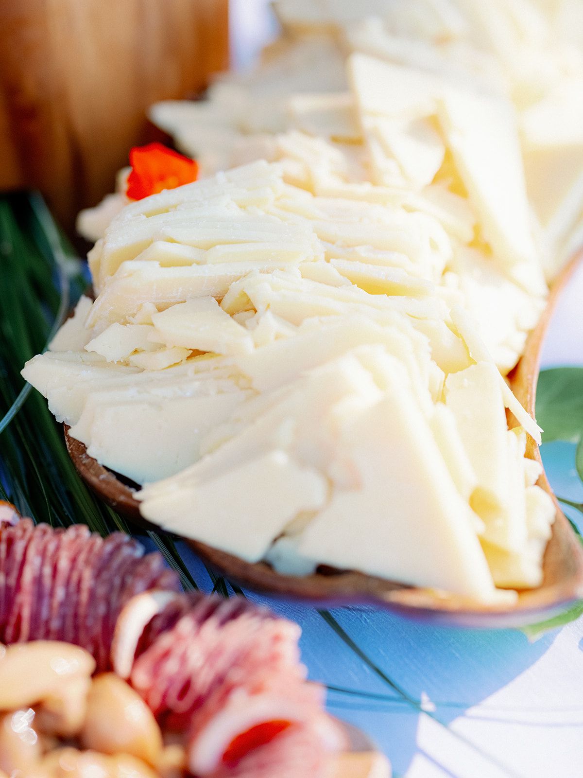 White sliced cheese piled on a tray with figs and nuts in the background