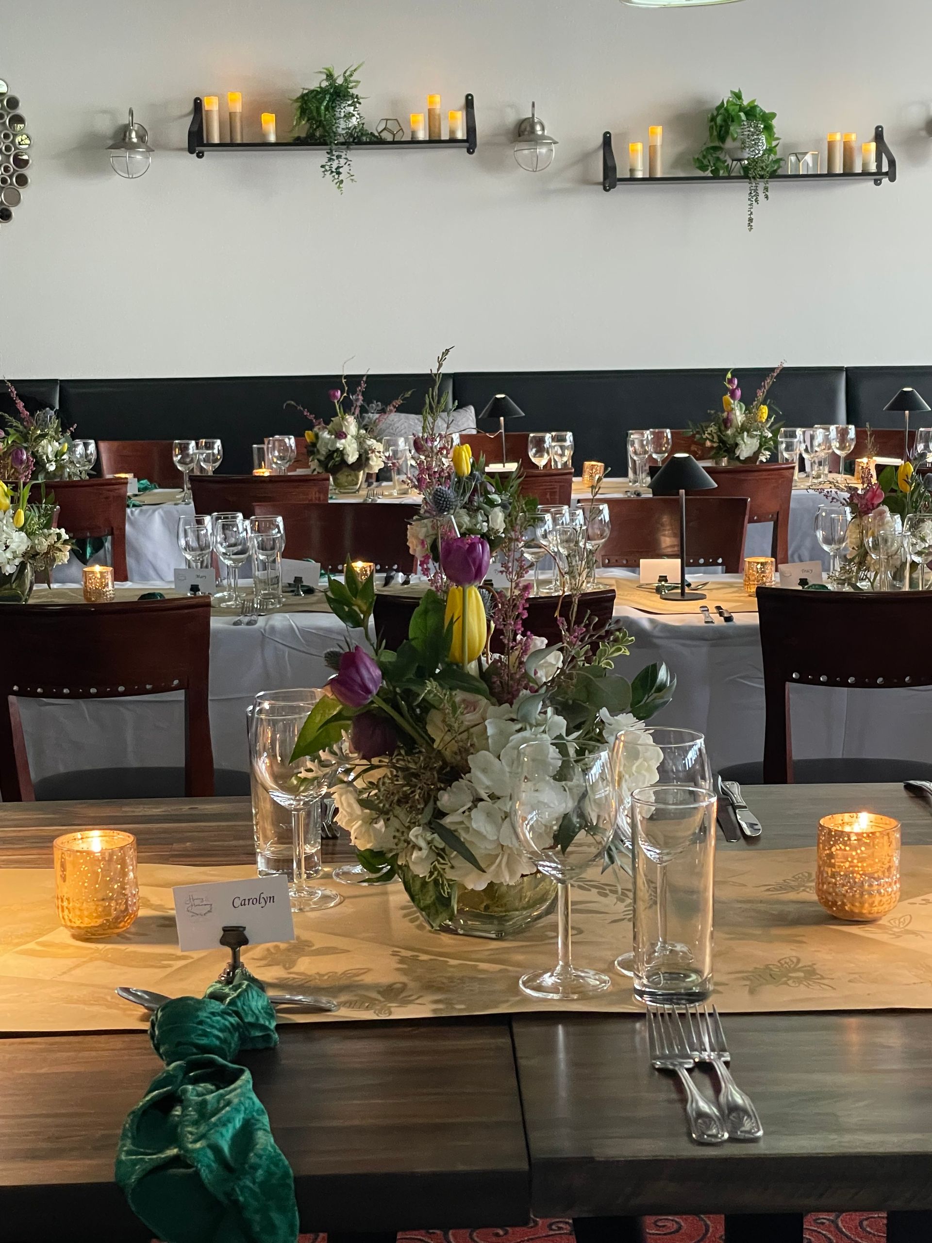Elegant banquet table with floral centerpieces, candles, and glassware in a softly lit dining room