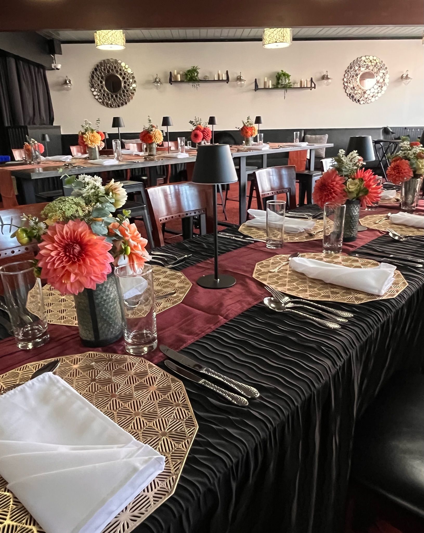 Elegant banquet table set with black and red decor, floral centerpieces, and folded napkins in a dining room