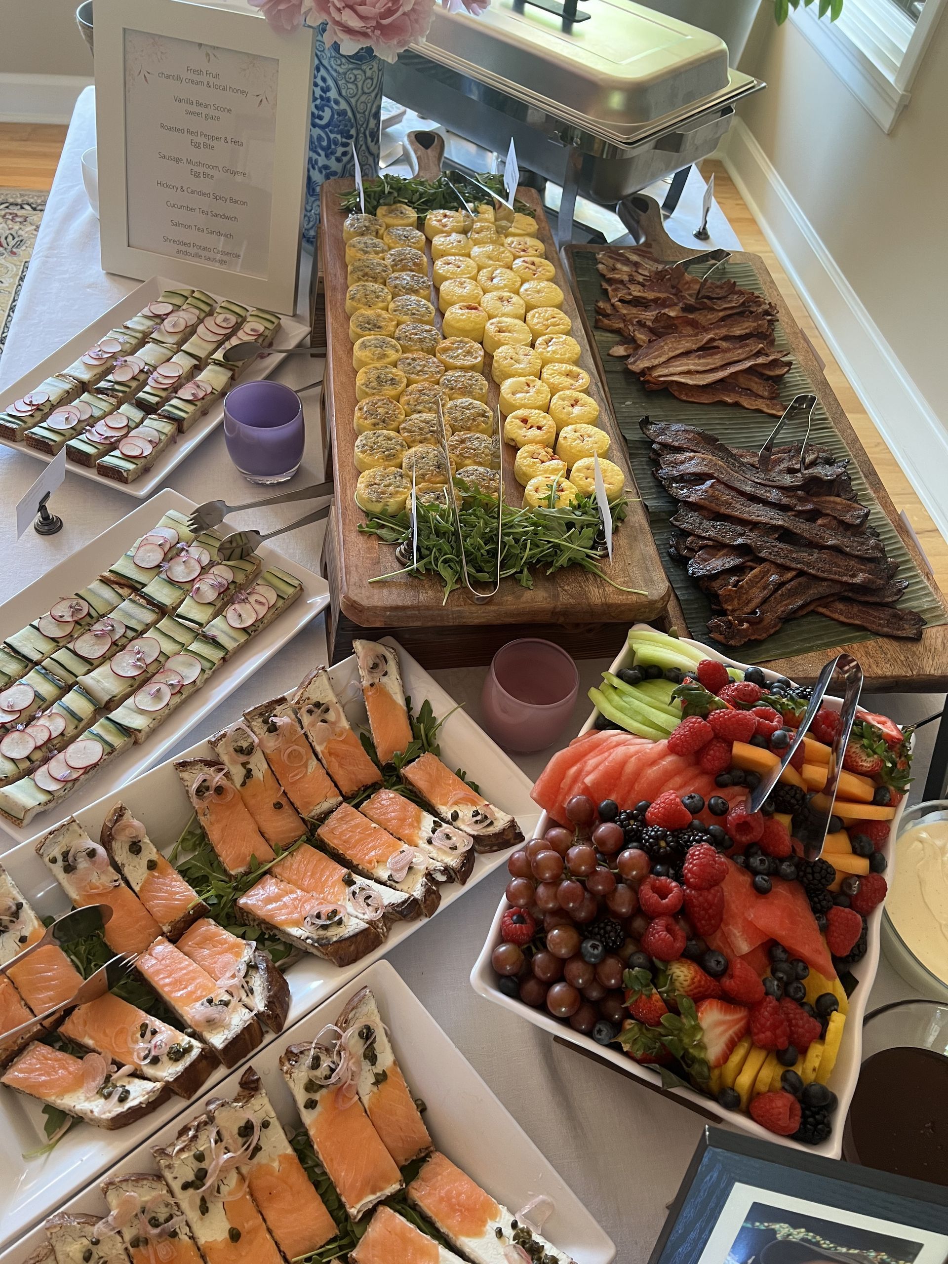 Charcuterie board with cheese, grapes, and appetizers, on wooden shelves, outdoor setting.