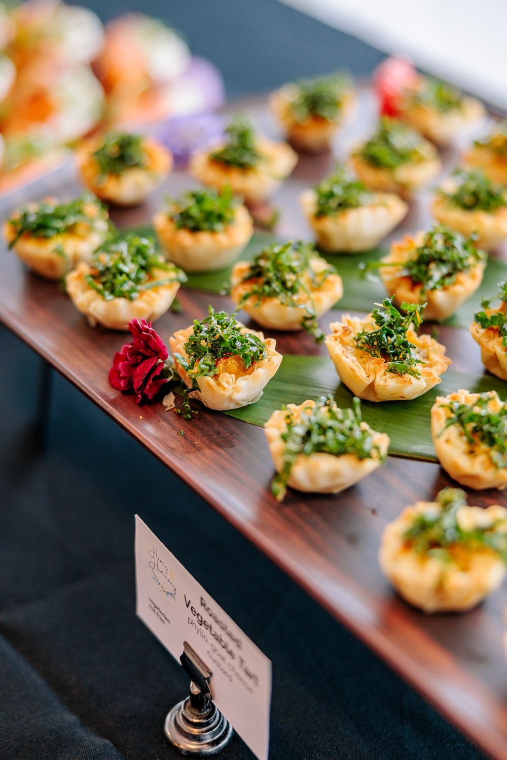 Tray of bite-size appetizers topped with green garnish at a buffet table