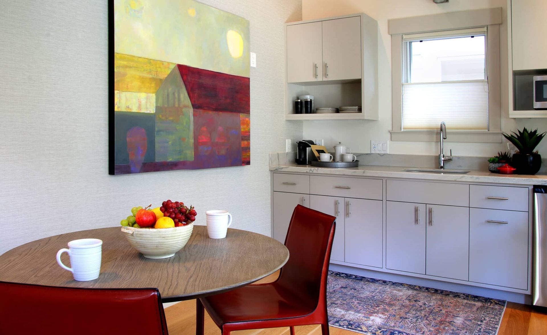 A kitchen with a bowl of fruit on the table