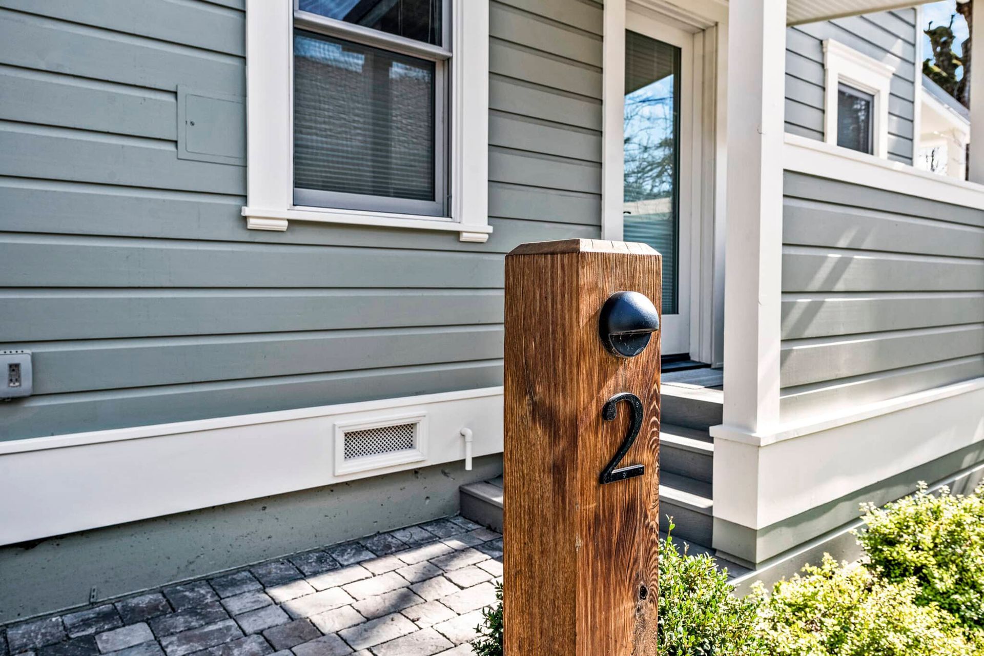 A wooden post with the number 2 on it is in front of a house.