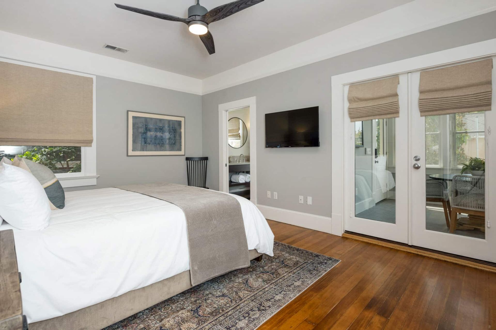 A bedroom with a bed , ceiling fan , television and sliding glass doors.