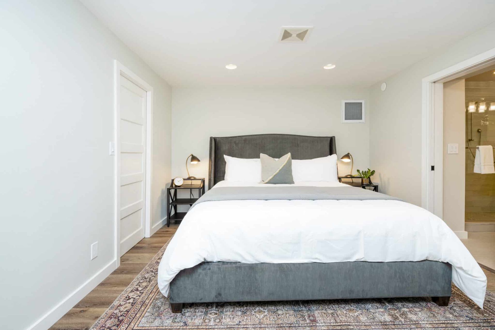A bedroom with a large bed and a rug on the floor.