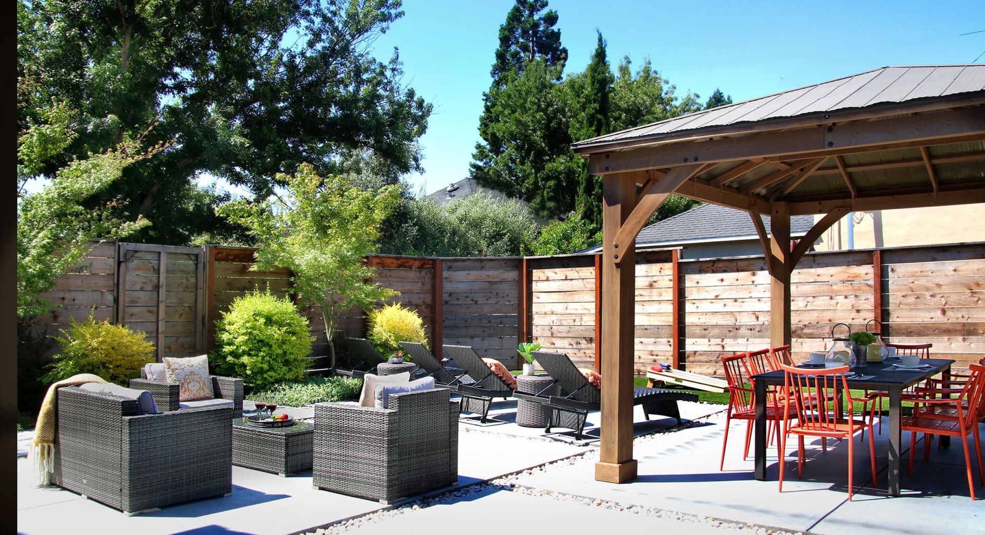 A patio with wicker furniture and a wooden gazebo
