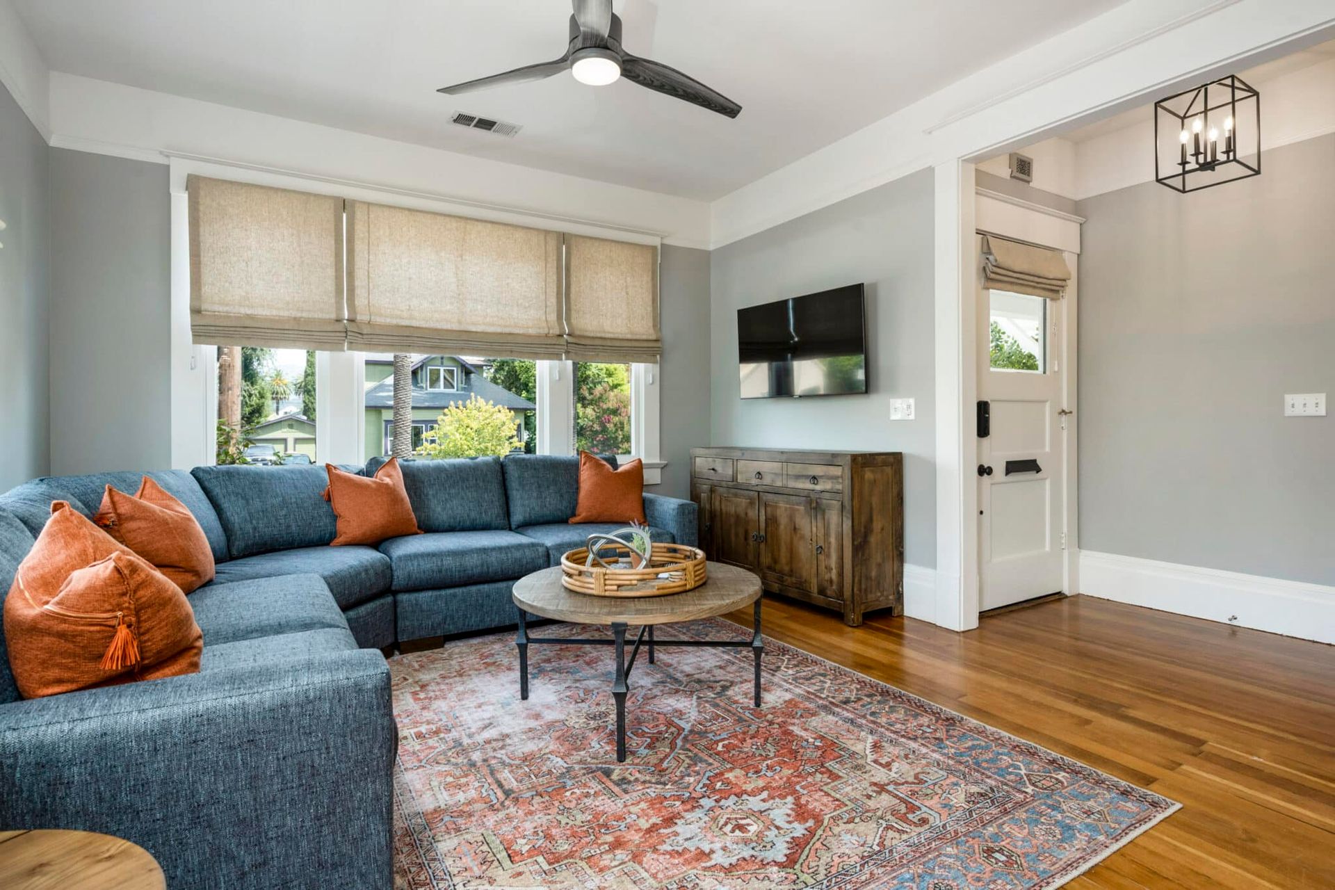 A living room with a blue sectional couch , a coffee table , and a ceiling fan.