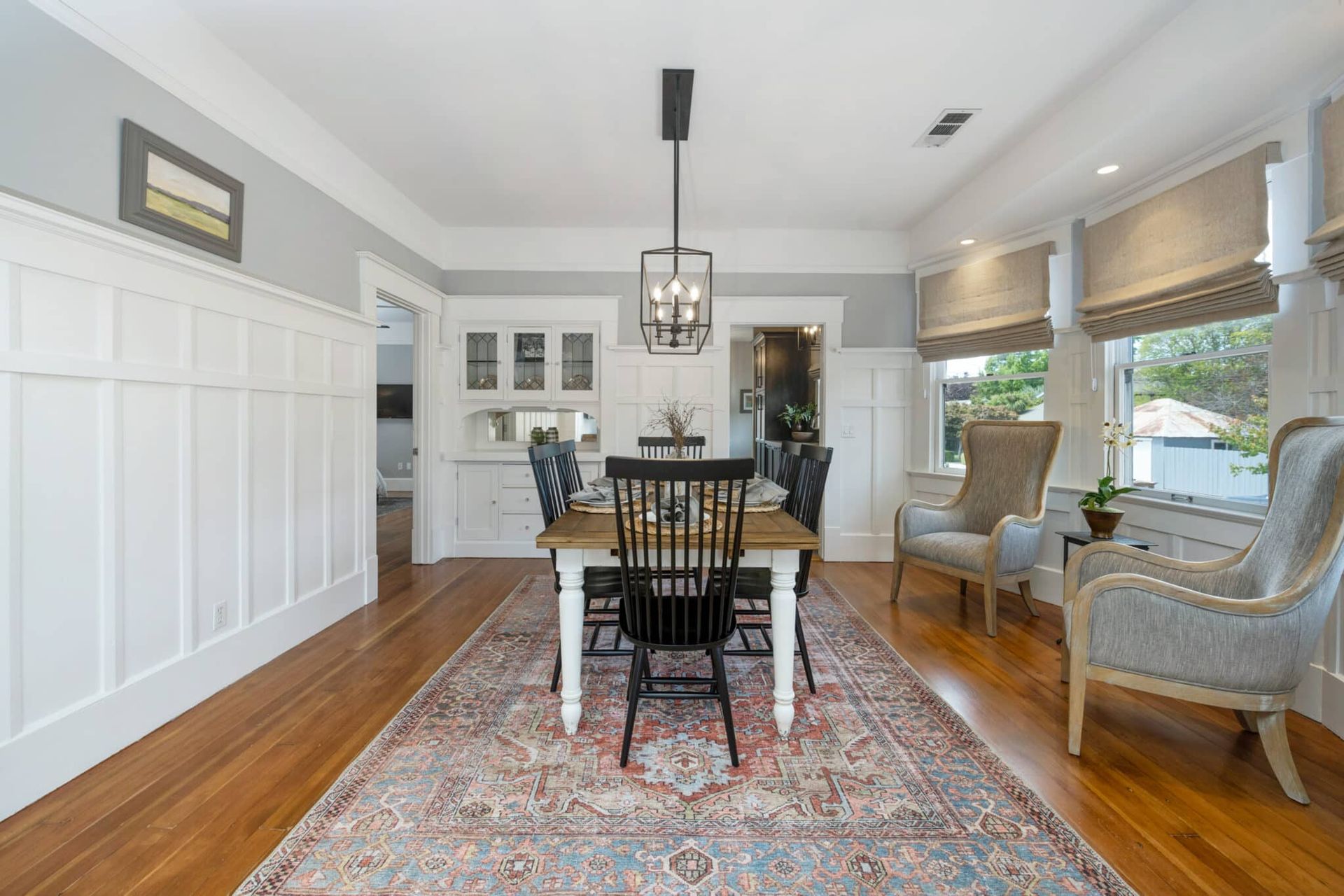 A dining room with a table and chairs and a rug.