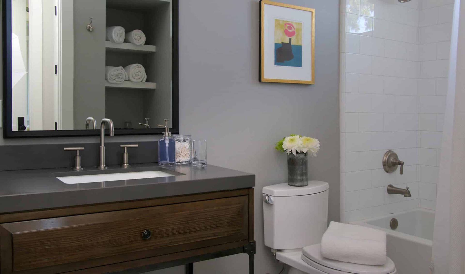 A bathroom with a toilet , sink , mirror and tub.
