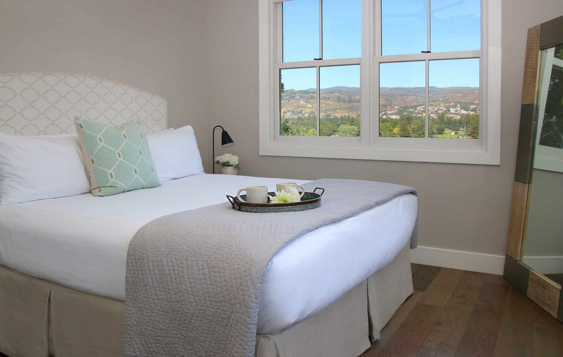 A bedroom with a bed and a window with a tray on the bed.