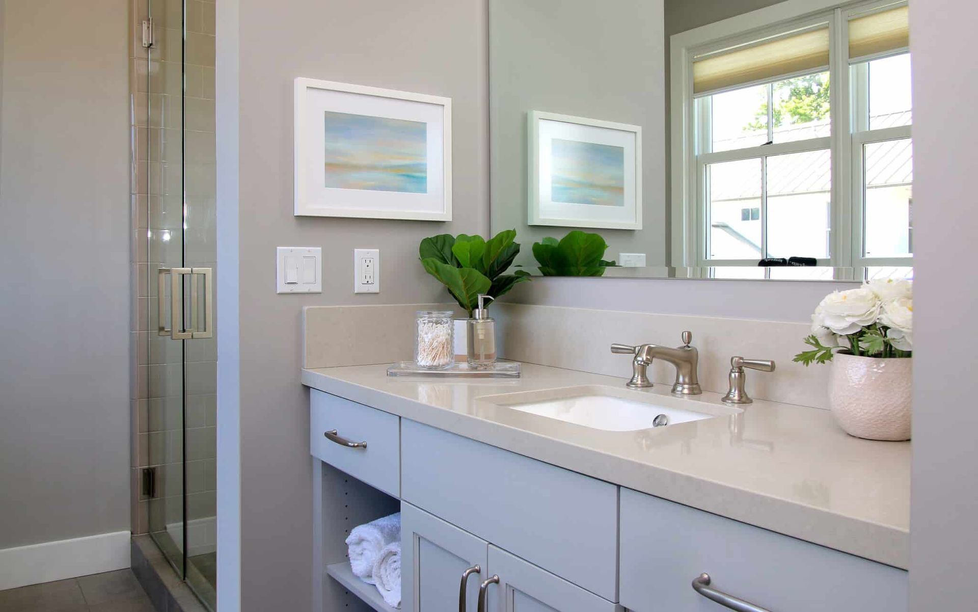 A bathroom with a sink , mirror and walk in shower.