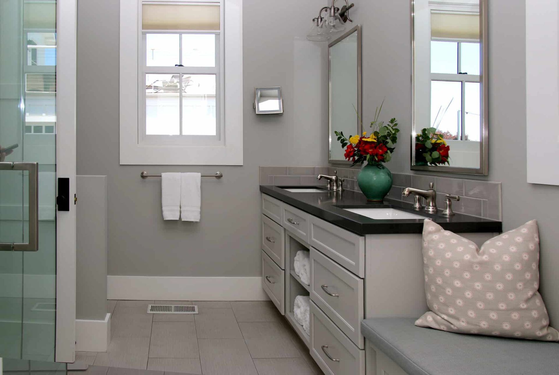 A bathroom with two sinks , two mirrors and a bench.